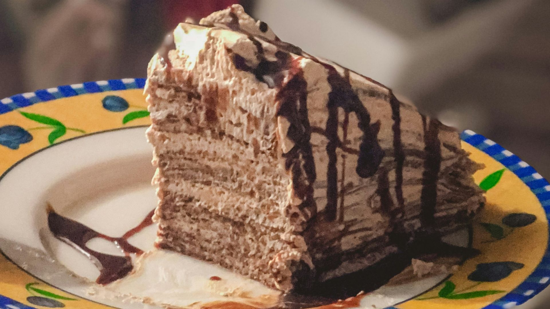 person holding white and blue plate with chocolate cake