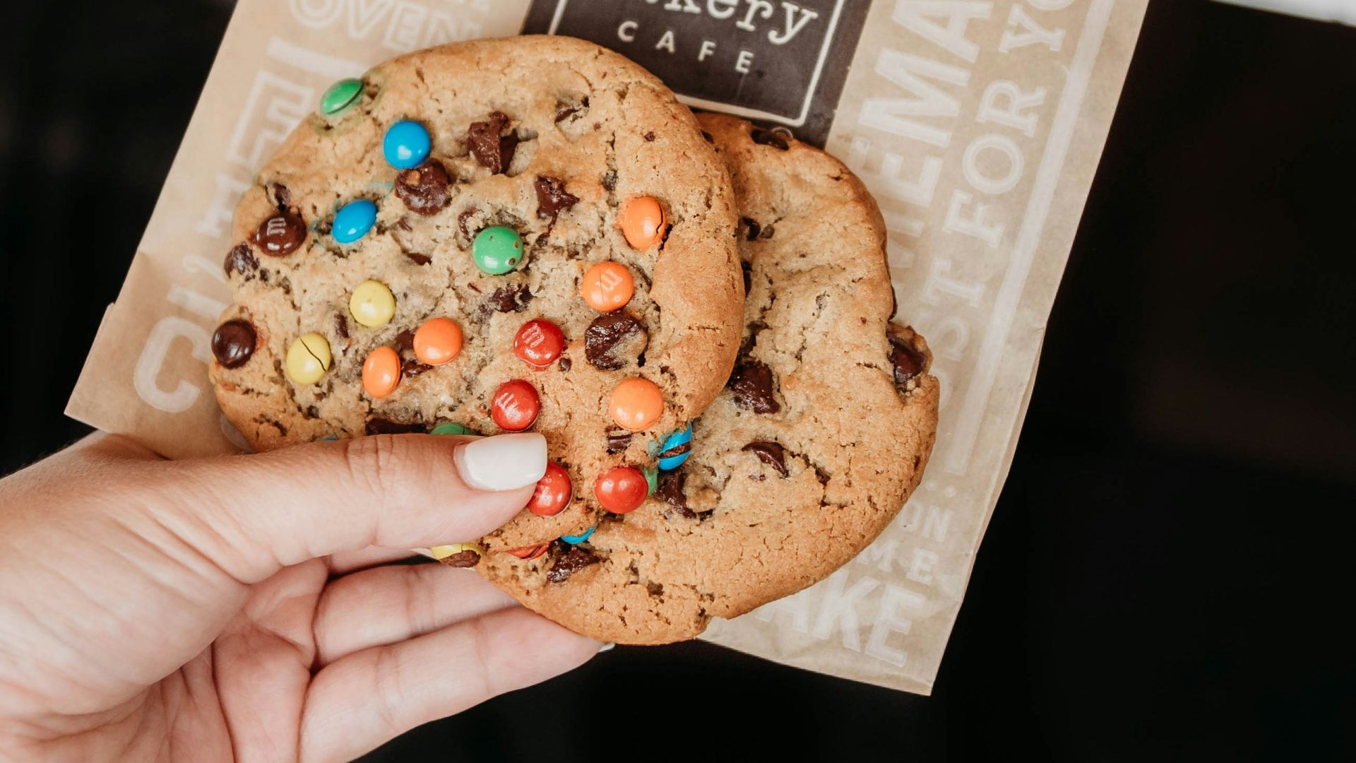 person holding brown and beige labeled pack