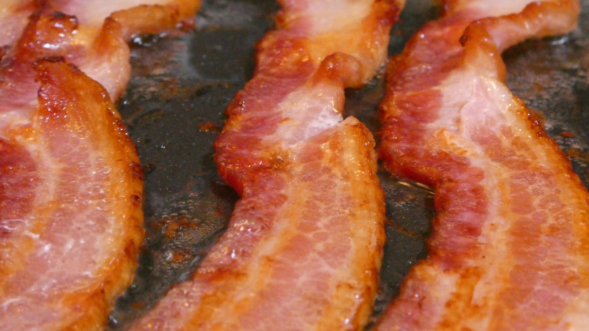 bacon is being cooked in a frying pan