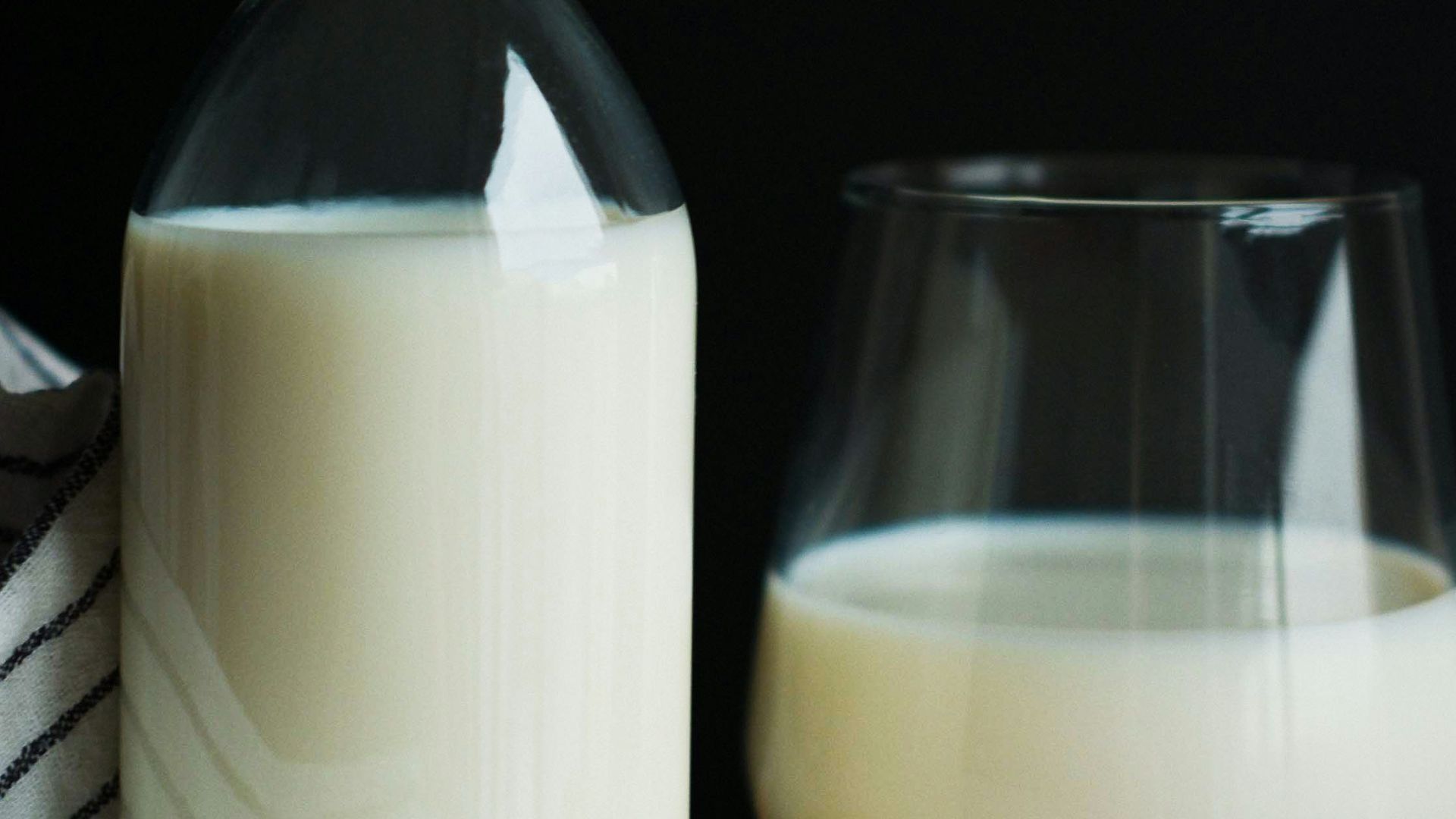 a bottle of milk next to a glass of milk