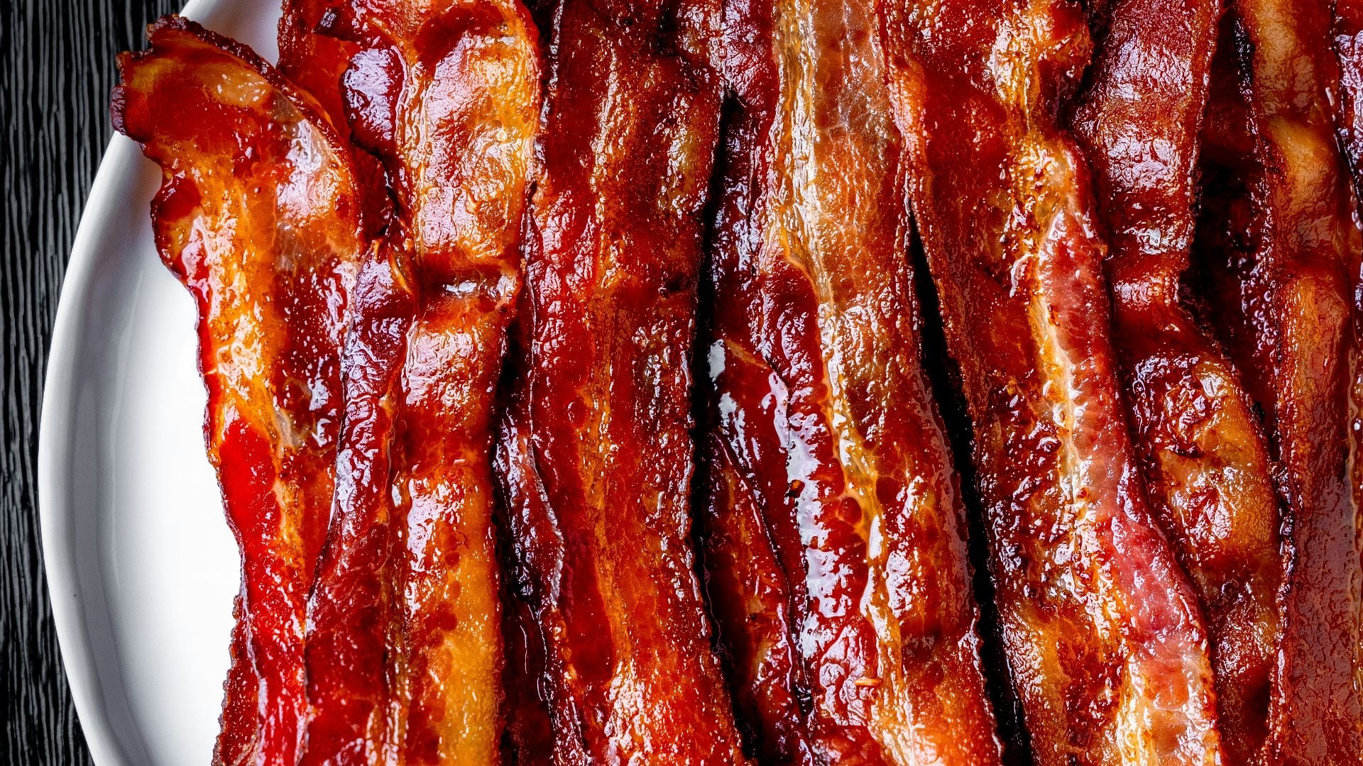 a white plate topped with bacon strips on top of a table