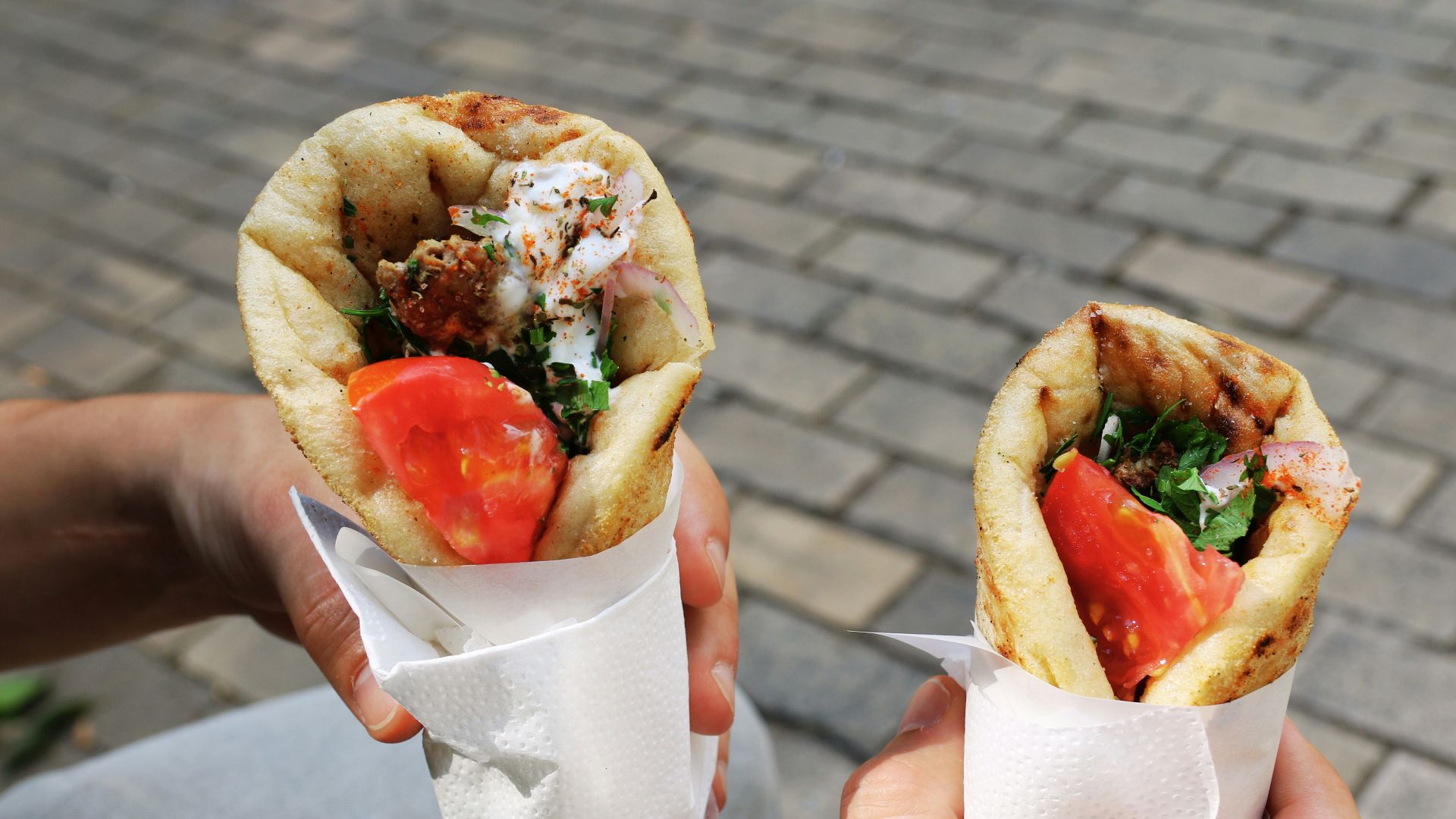 A person holding two sandwiches in their hands