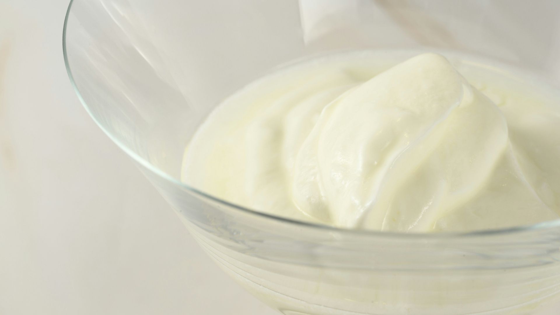 a glass bowl filled with cream on top of a table