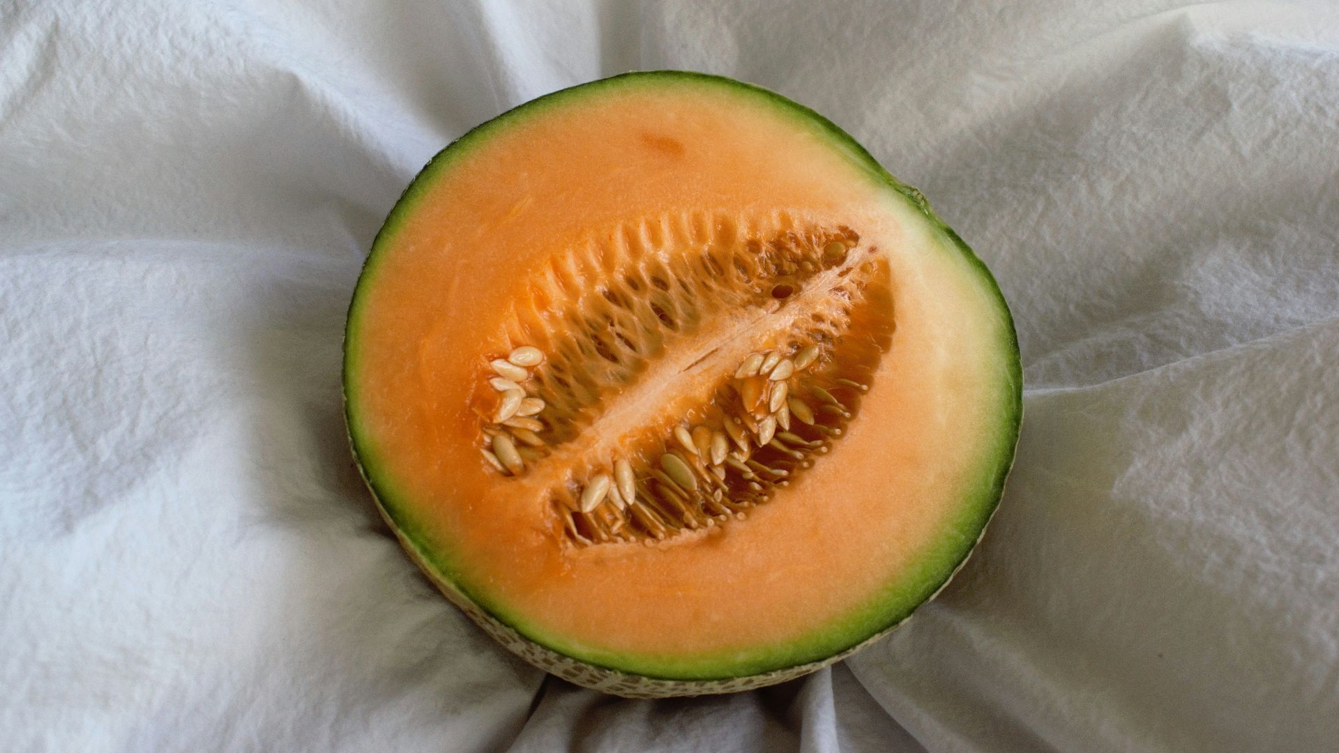 a cut in half melon sitting on top of a white cloth