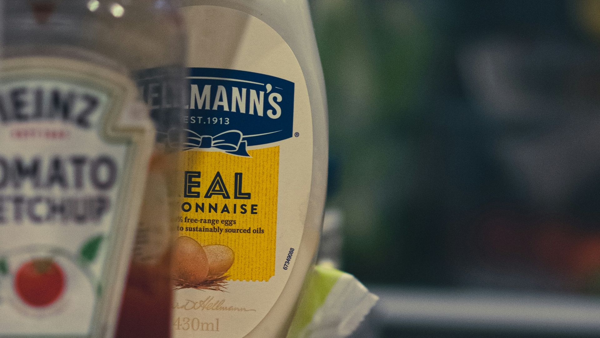 a container of mayonnaise and a bottle of ketchup on a shelf