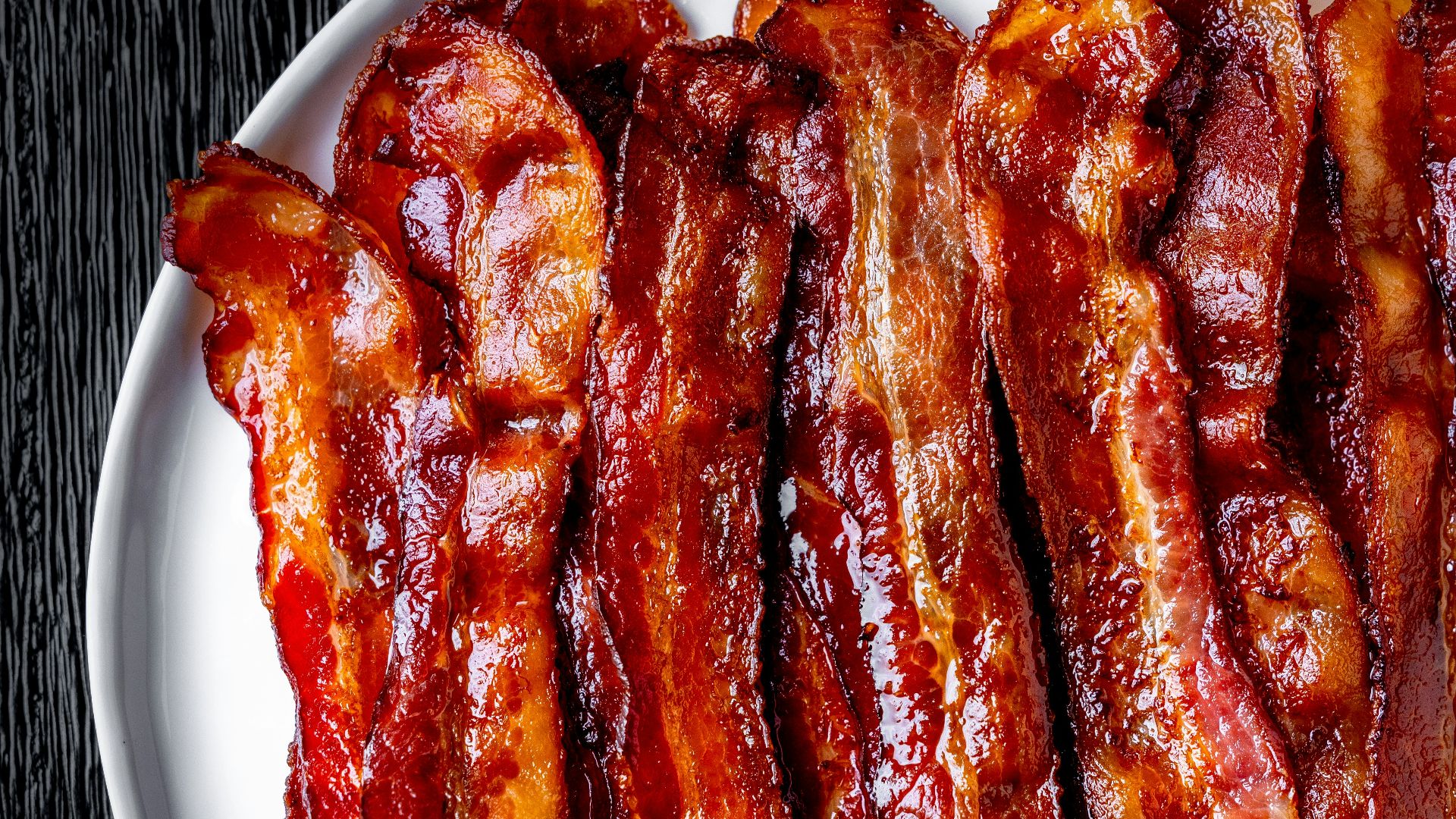 a white plate topped with bacon strips on top of a table