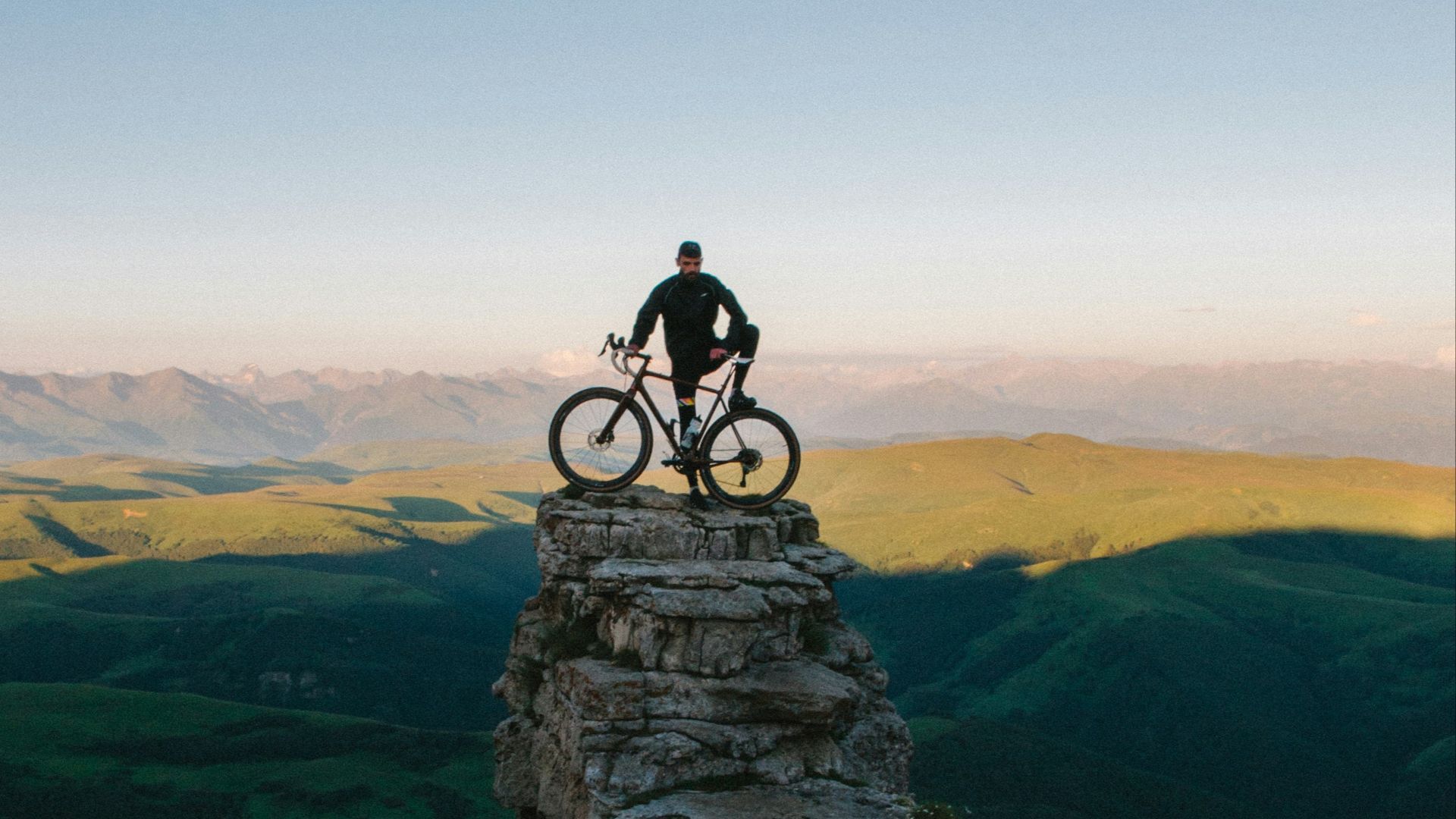 man holding bike while standing on gray mountain