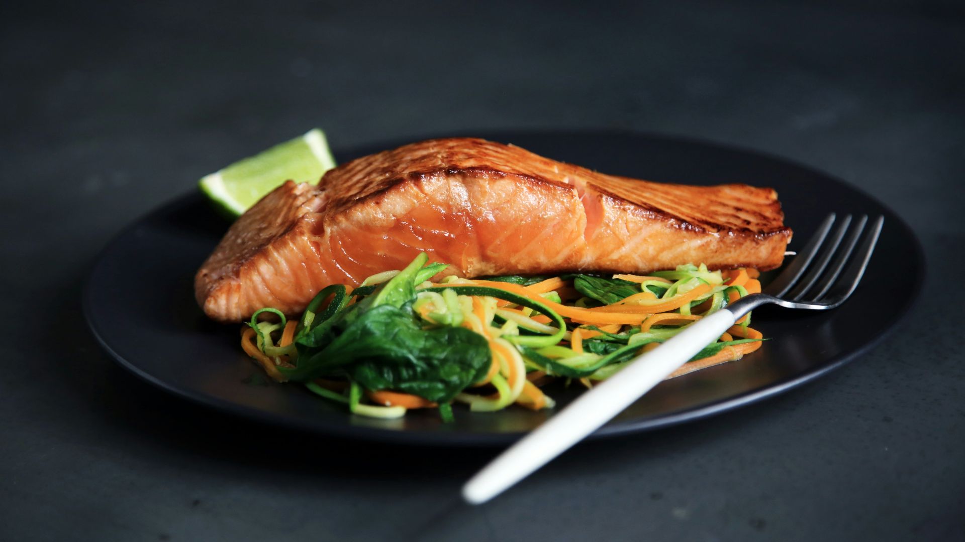 grilled fish, cooked vegetables, and fork on plate