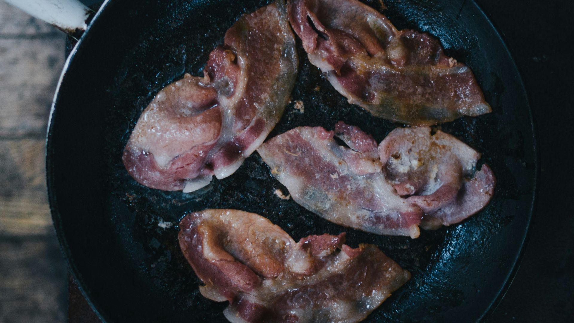 bacon on top of black cast-iron skillet