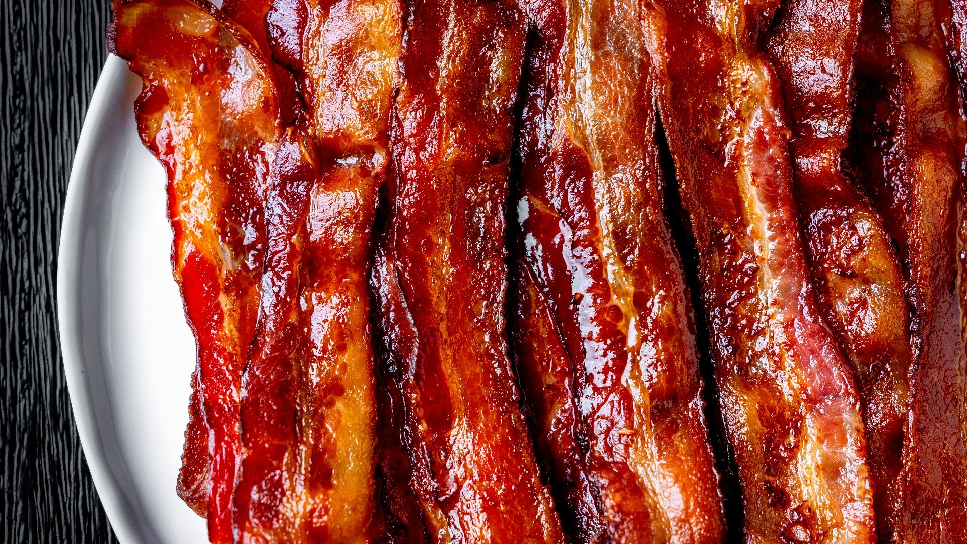 a white plate topped with bacon strips on top of a table