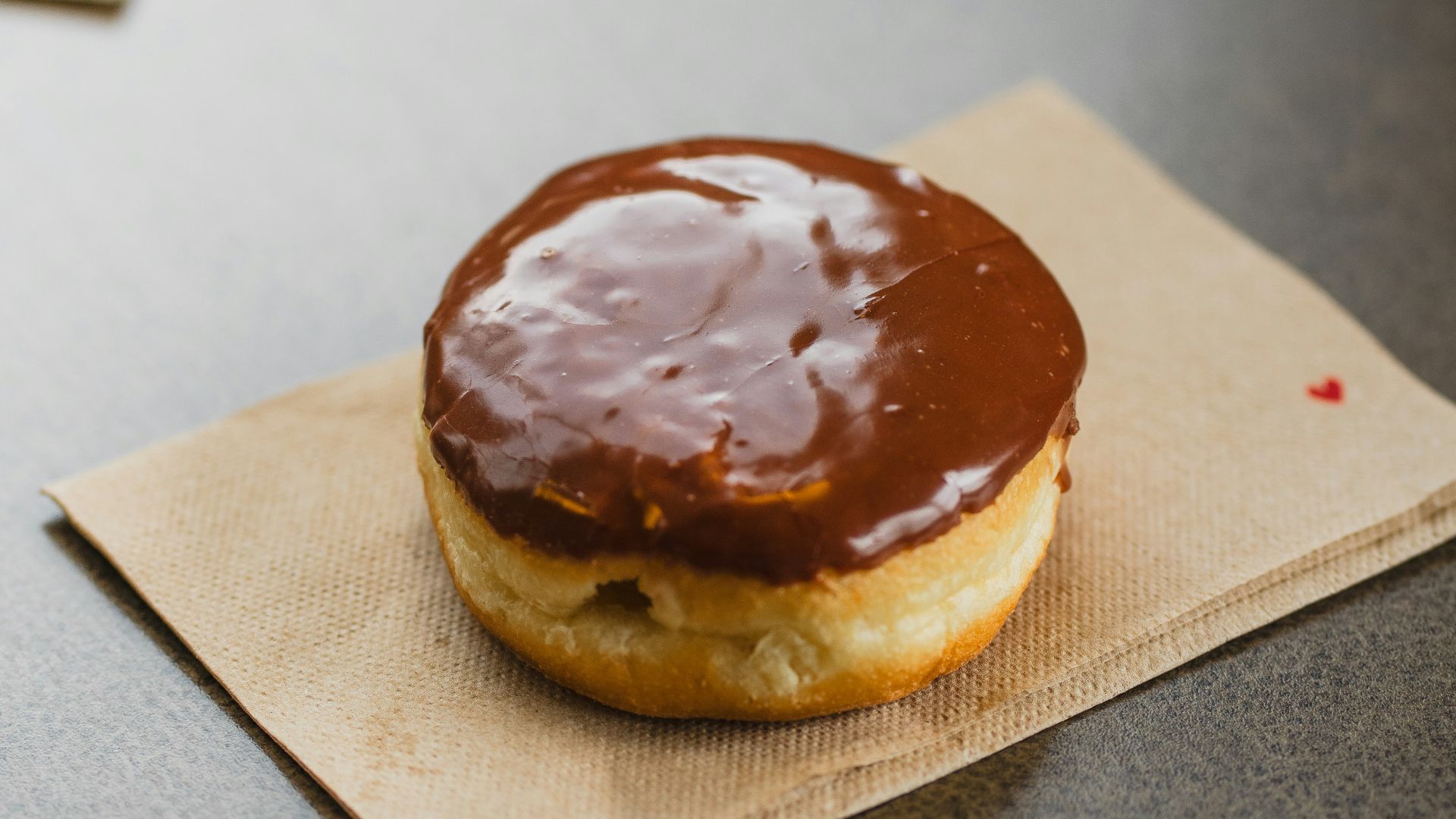 a chocolate covered doughnut sitting on top of a napkin