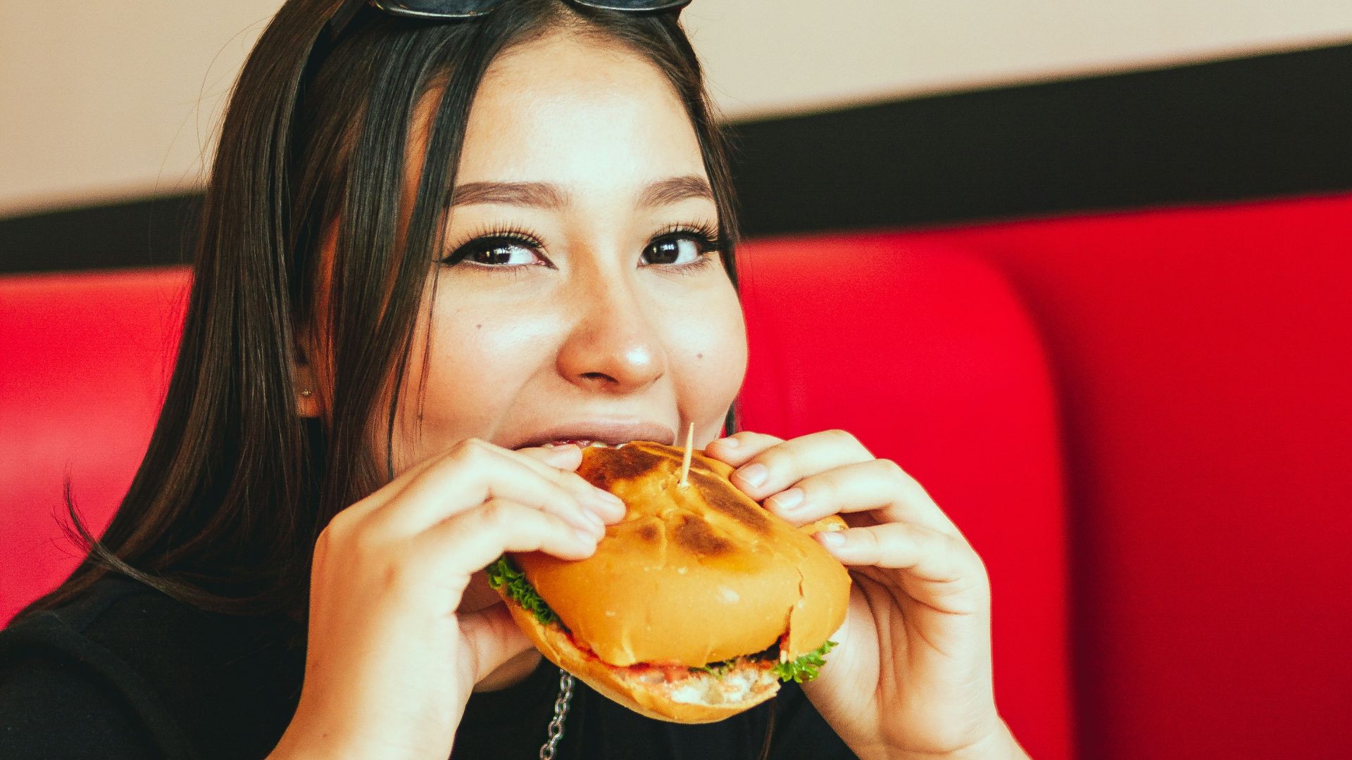 woman in black long sleeve shirt eating burger