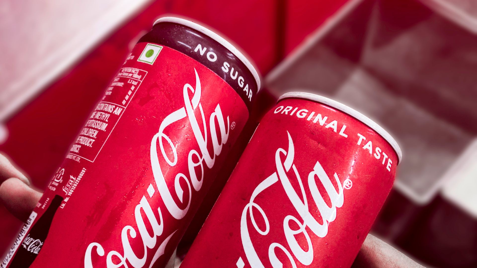 two red-and-white Coca-Cola cans