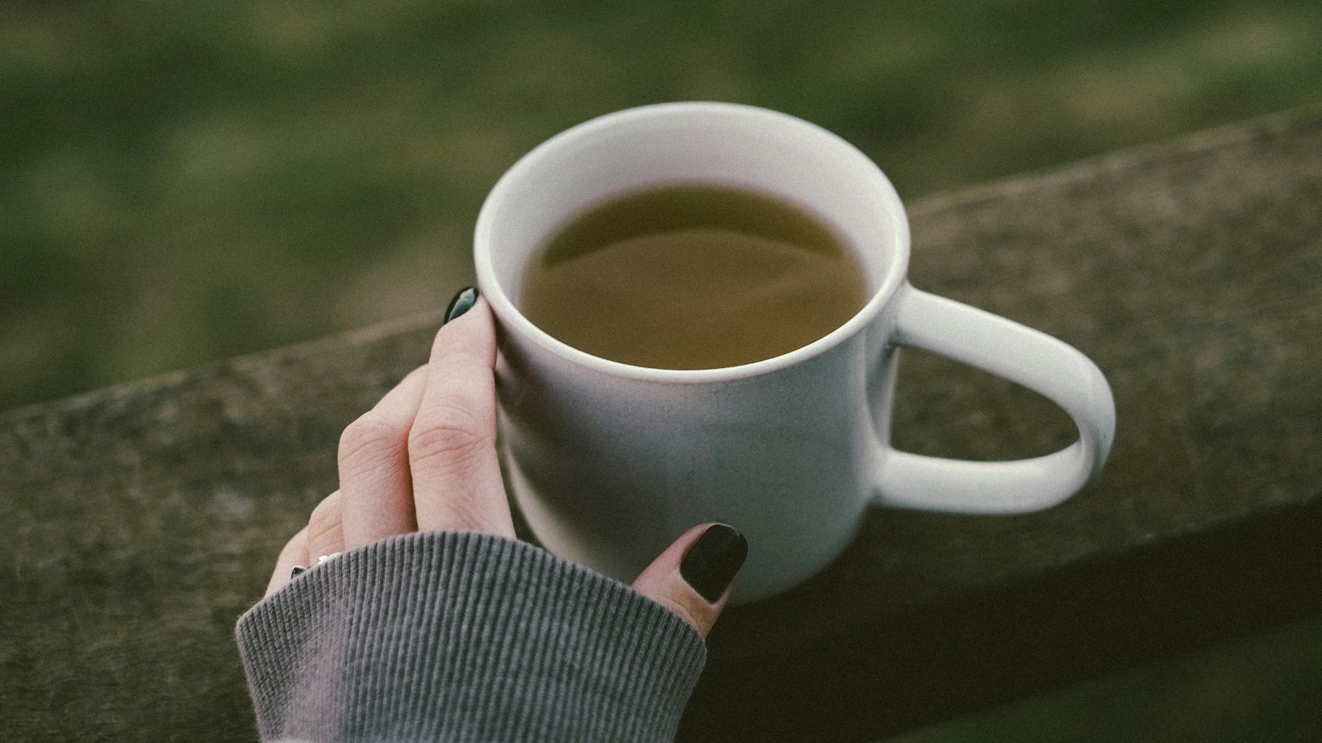 a woman's hand holding a cup of coffee