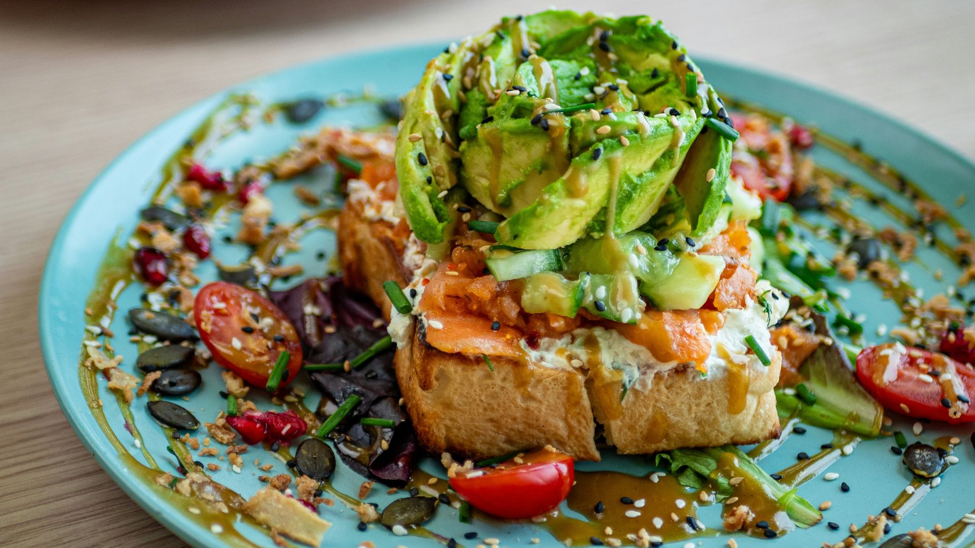 a blue plate topped with a piece of bread covered in veggies