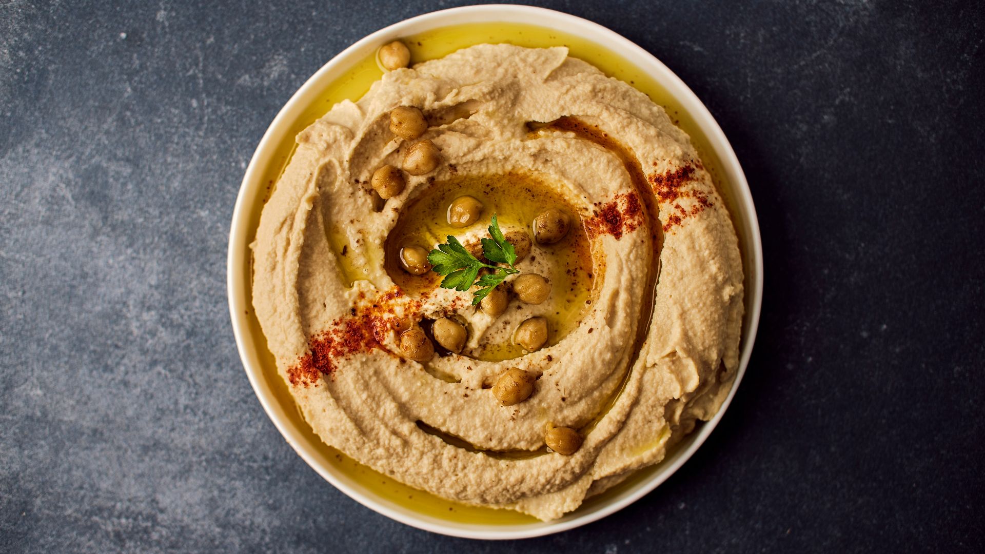 a bowl of hummus with a garnish on top