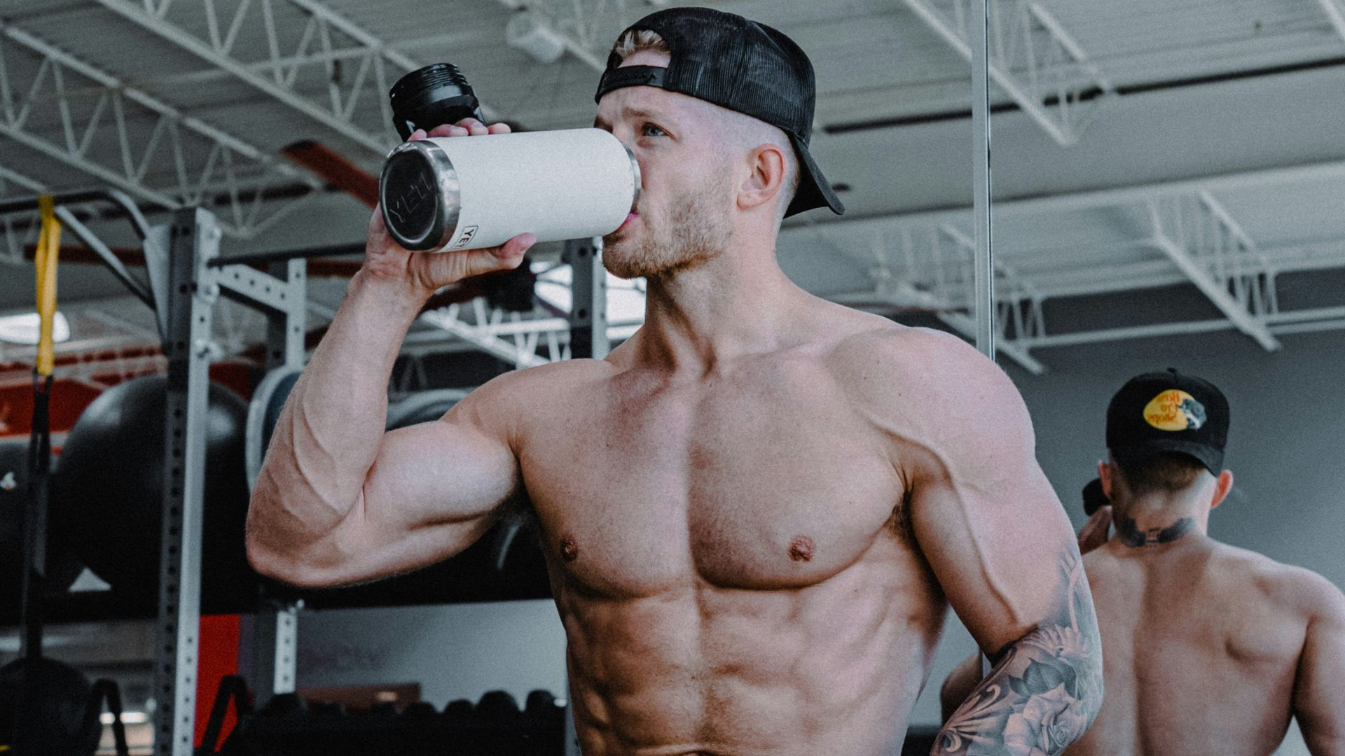 a shirtless man drinking from a white cup