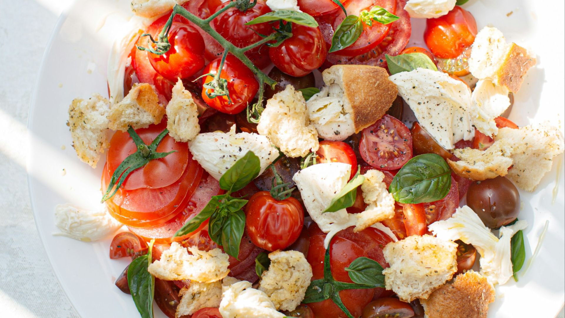 sliced tomato and green leaf vegetable on white ceramic plate