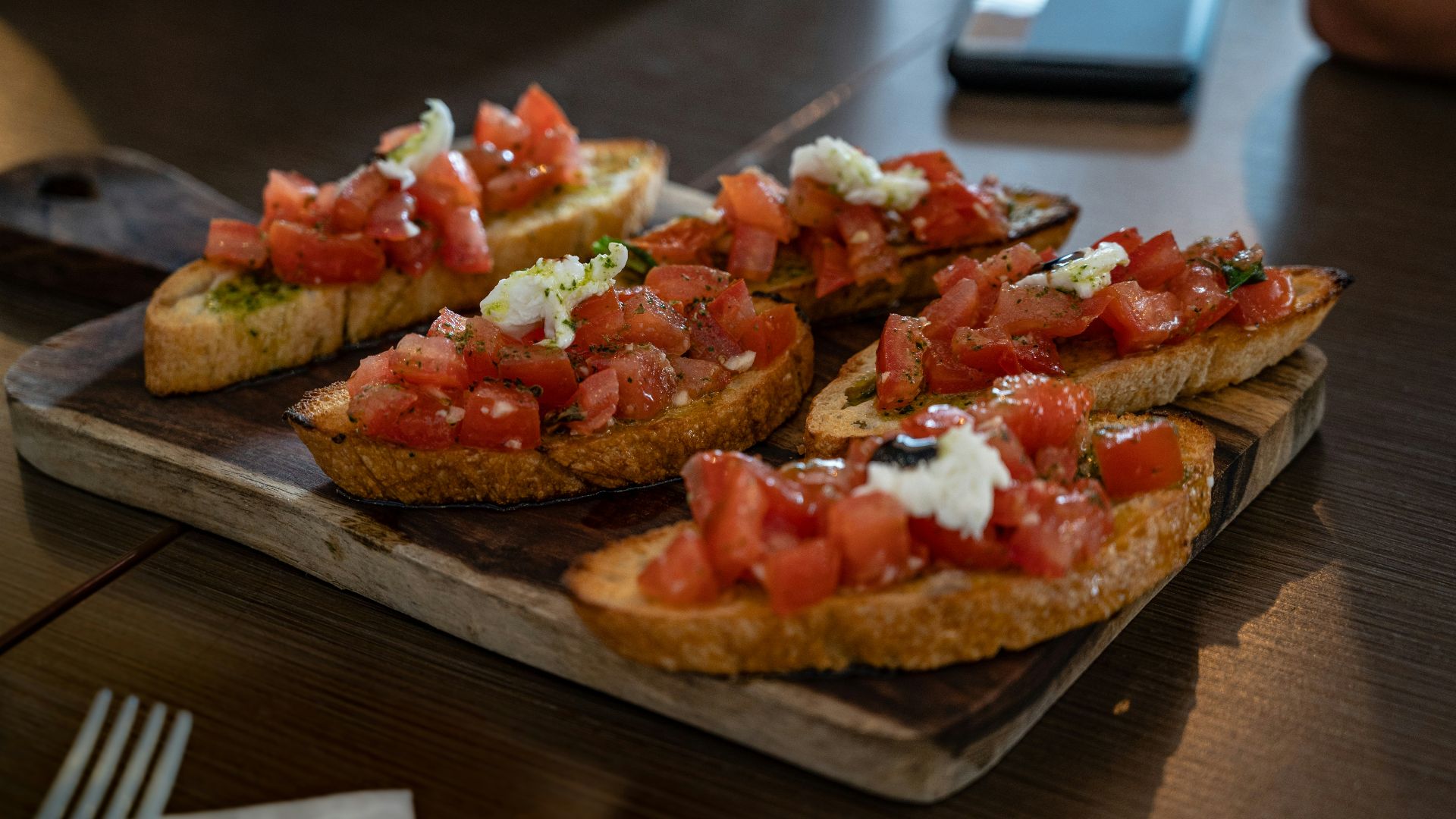 brown bread with tomato and green vegetable on brown wooden table