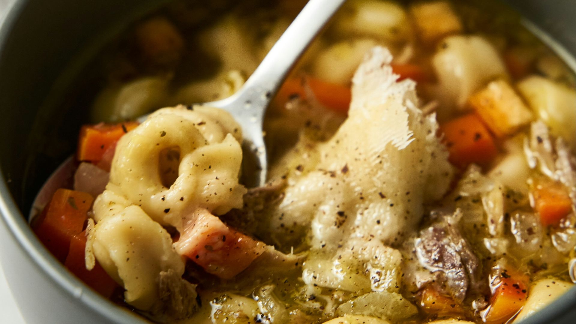 a bowl of pasta soup with a spoon in it
