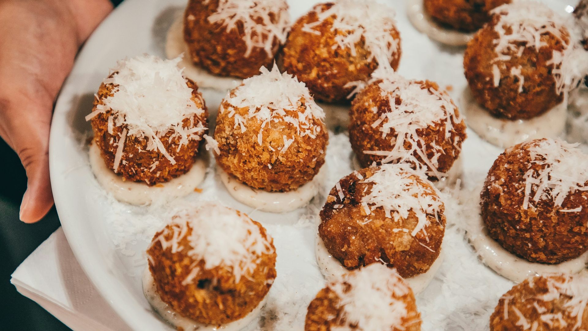 a person holding a plate of food with powdered sugar on it