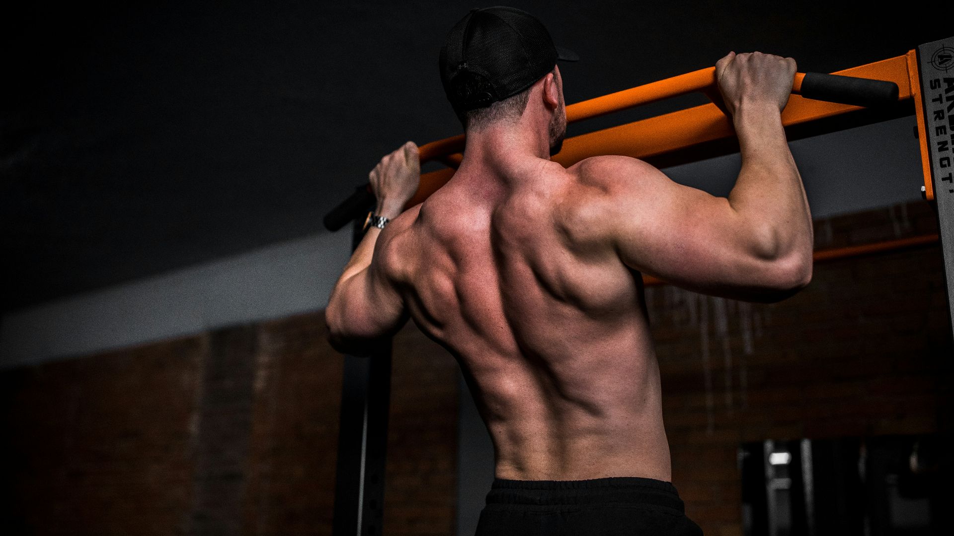 topless man in black shorts holding orange bar