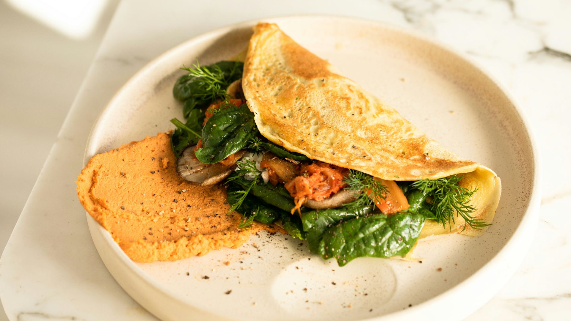 a white plate topped with an omelet and greens