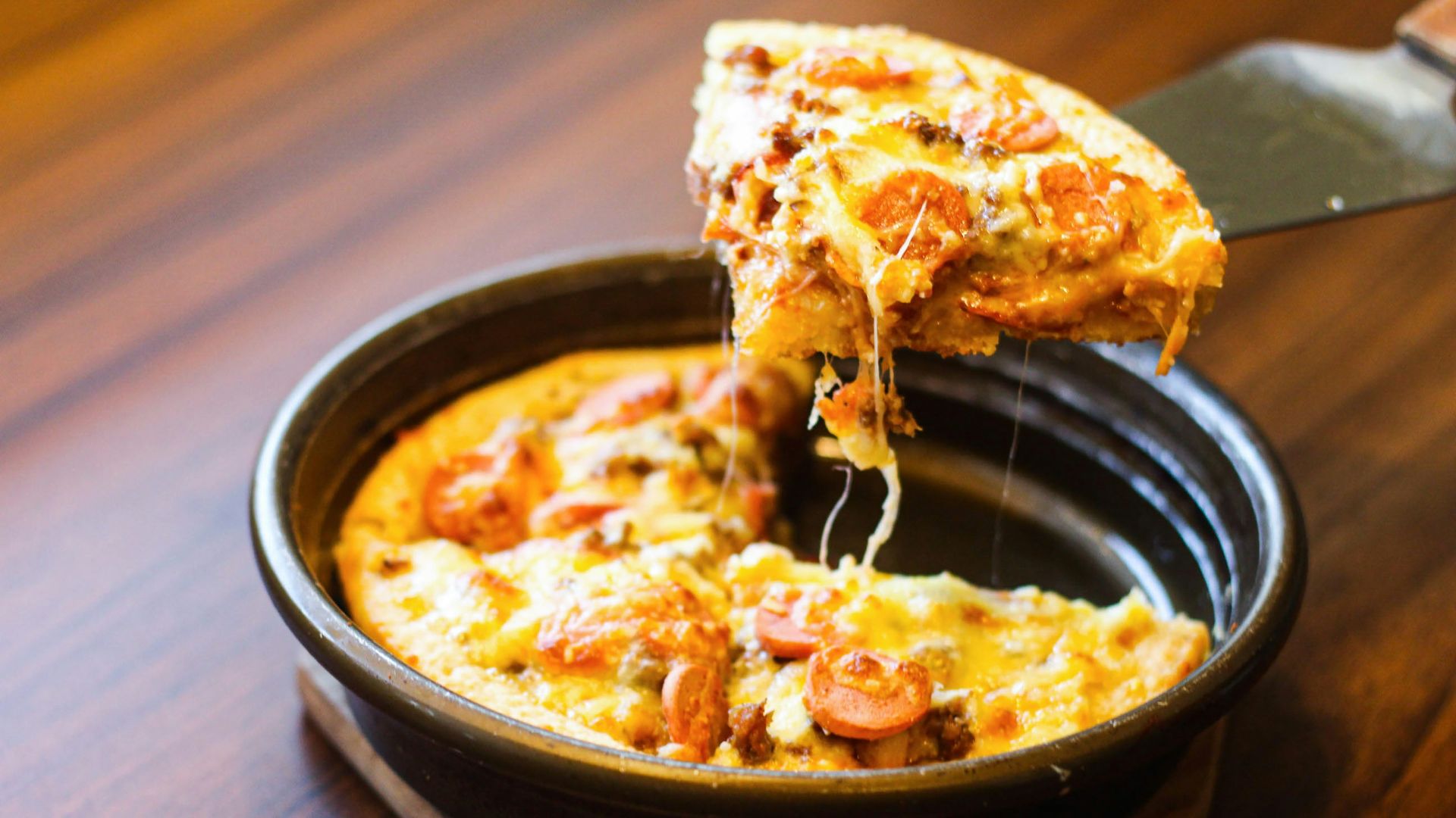 a person taking a slice of pizza from a pan