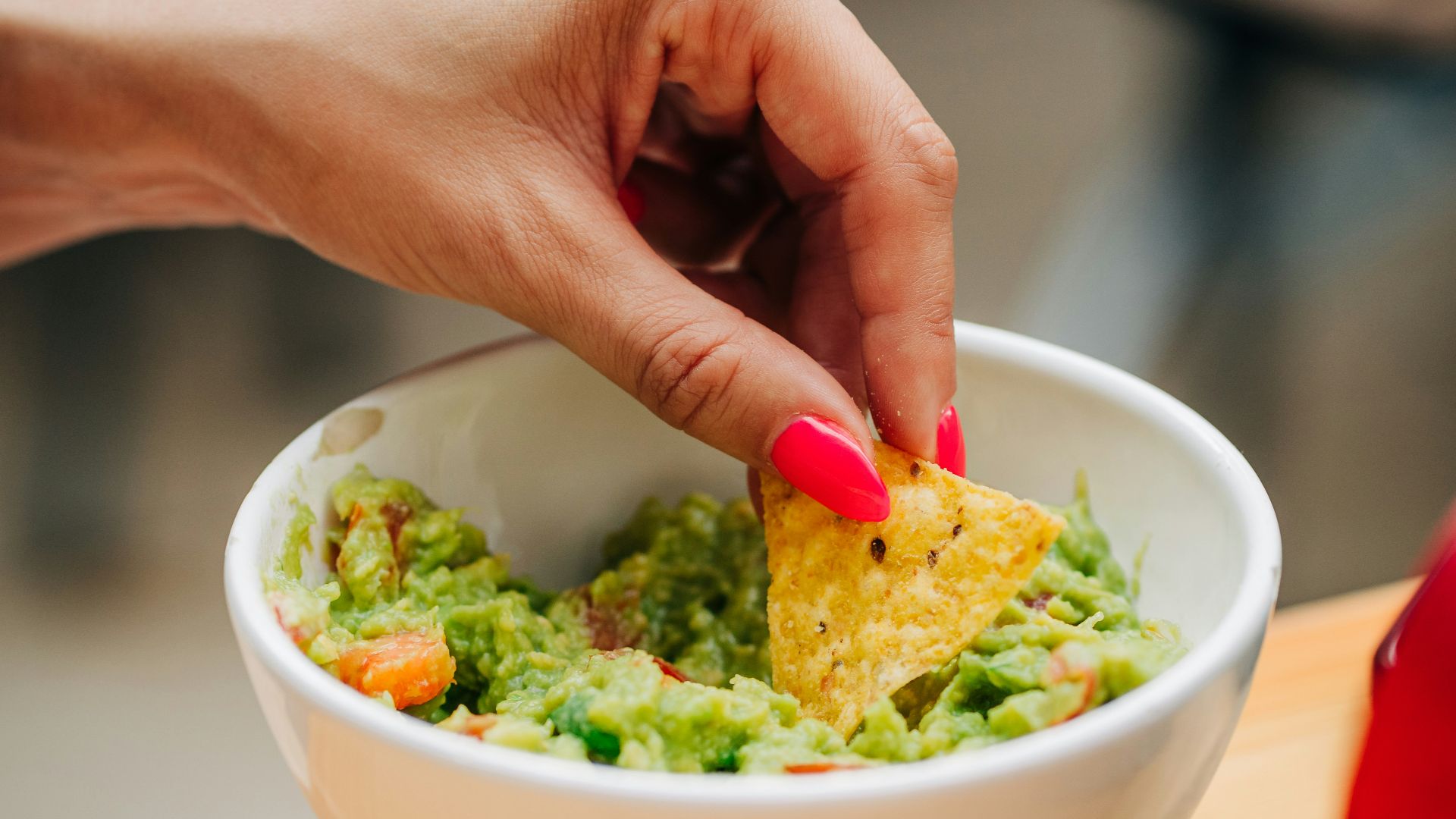a person dipping a tortilla into a bowl of guacamole