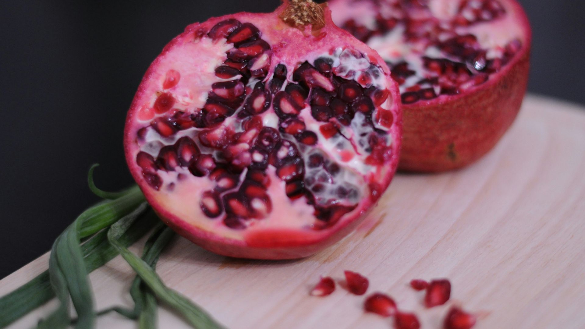 A pomegranate cut in half on a cutting board