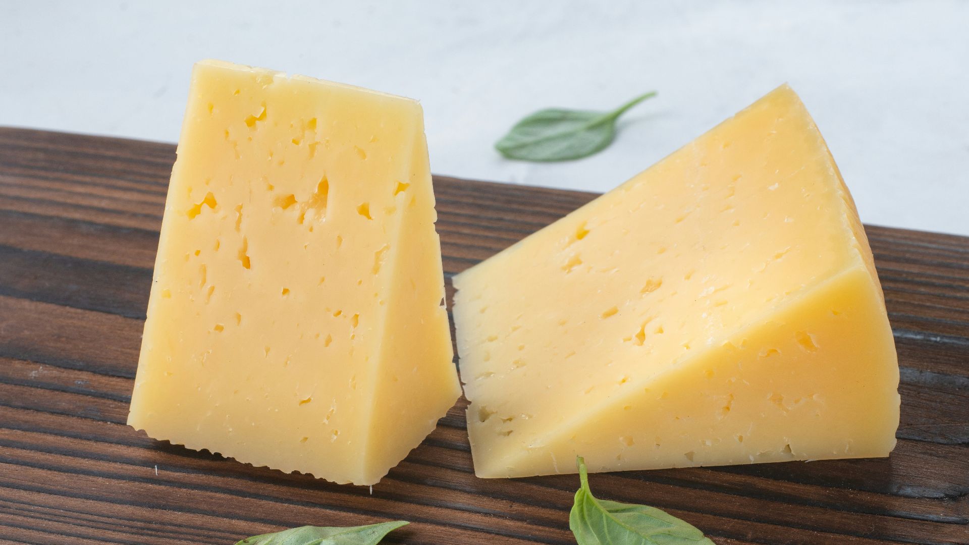 a couple of pieces of cheese sitting on top of a wooden cutting board