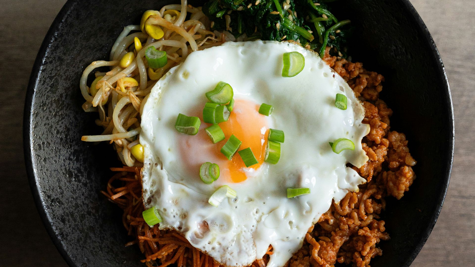a black bowl filled with noodles and an egg