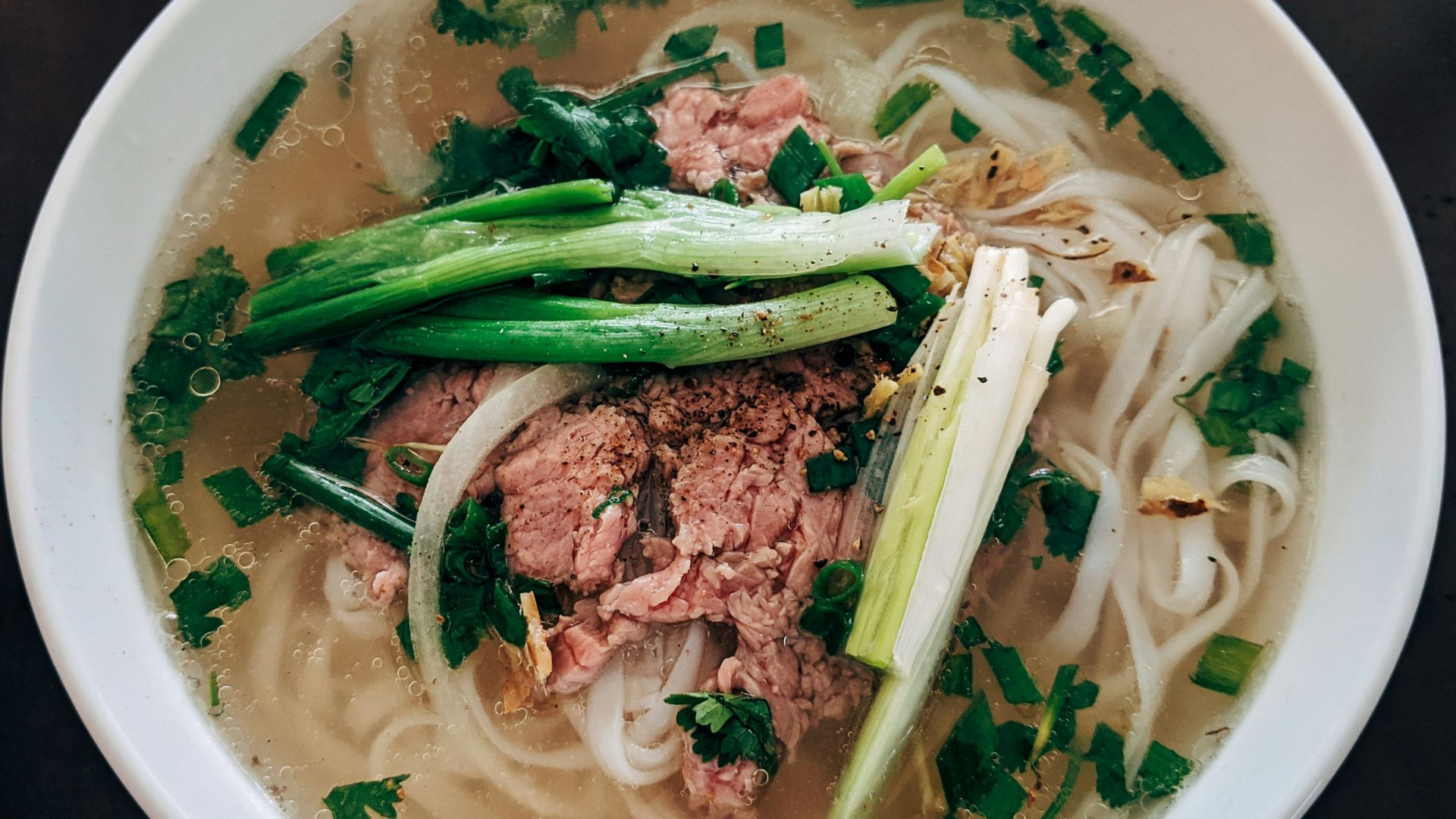 white noodle soup with green leaf vegetable in white ceramic bowl