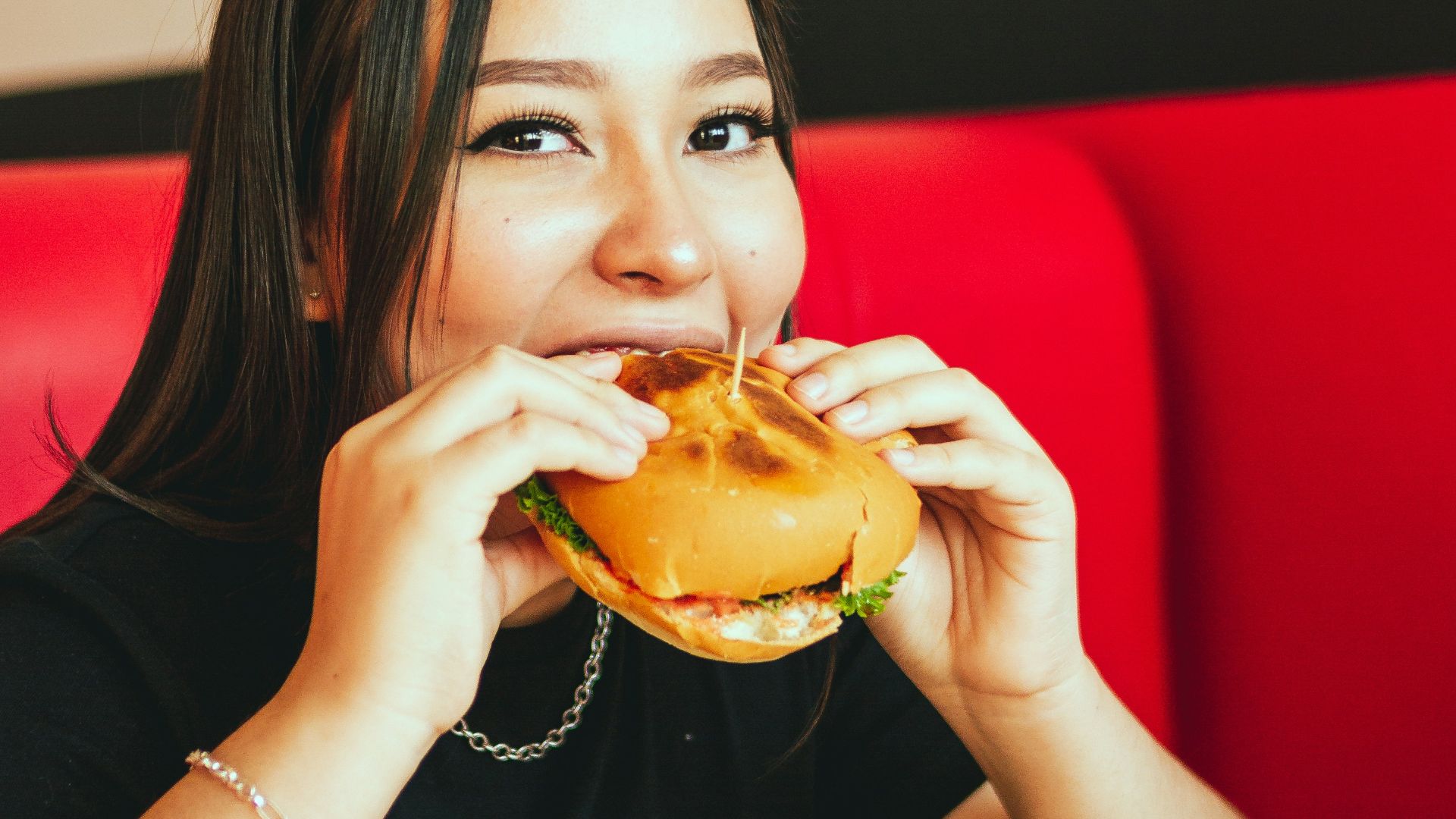 woman in black long sleeve shirt eating burger