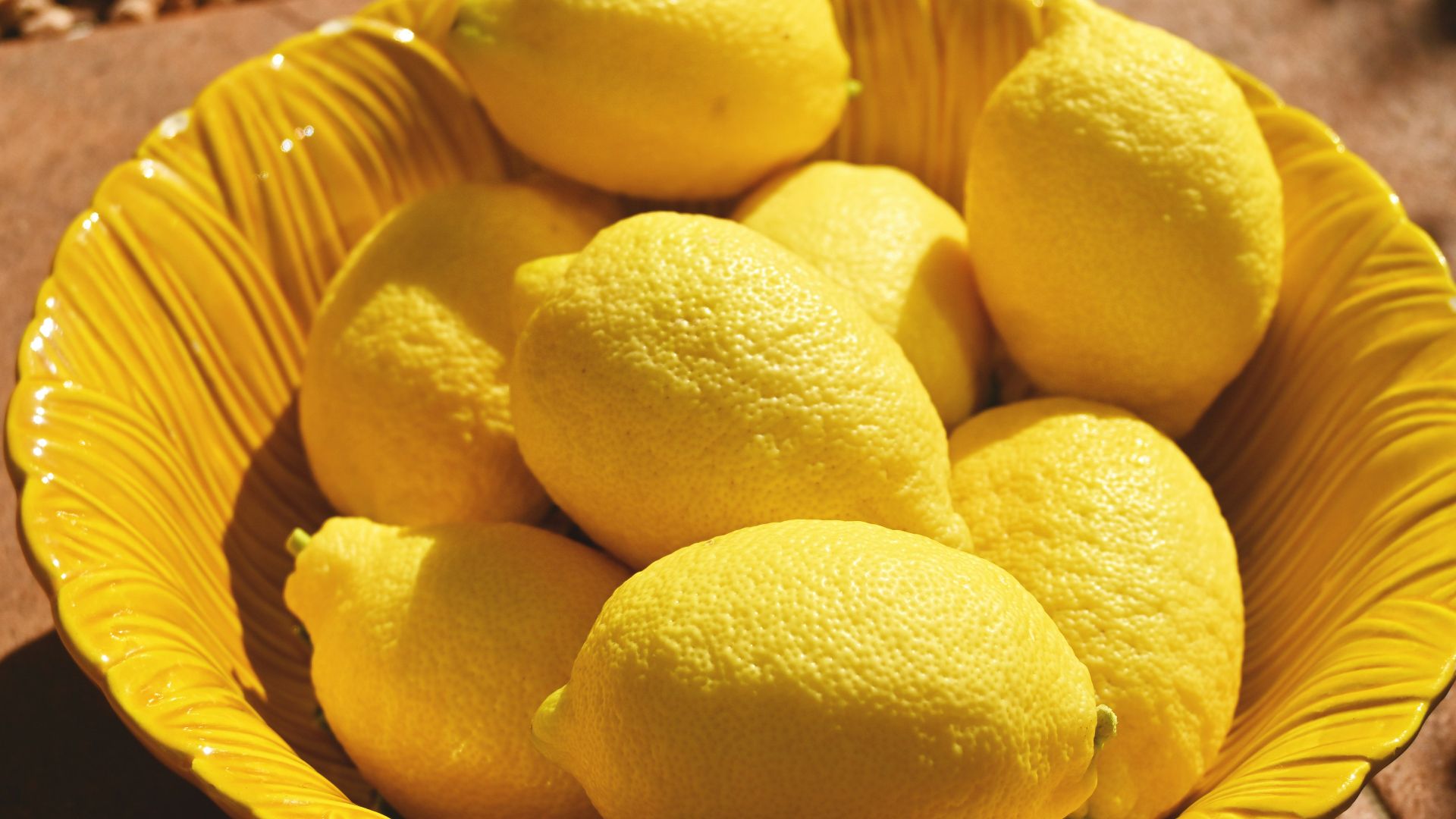 a yellow bowl filled with lemons on a table