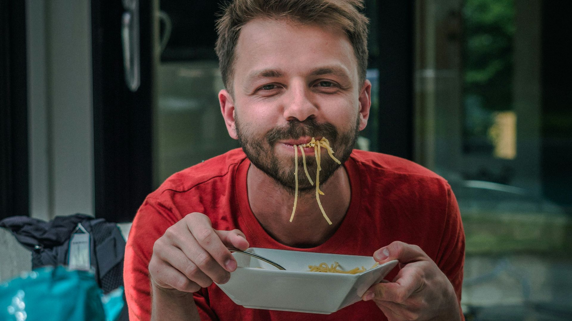 man in red crew neck t-shirt holding white and red labeled can
