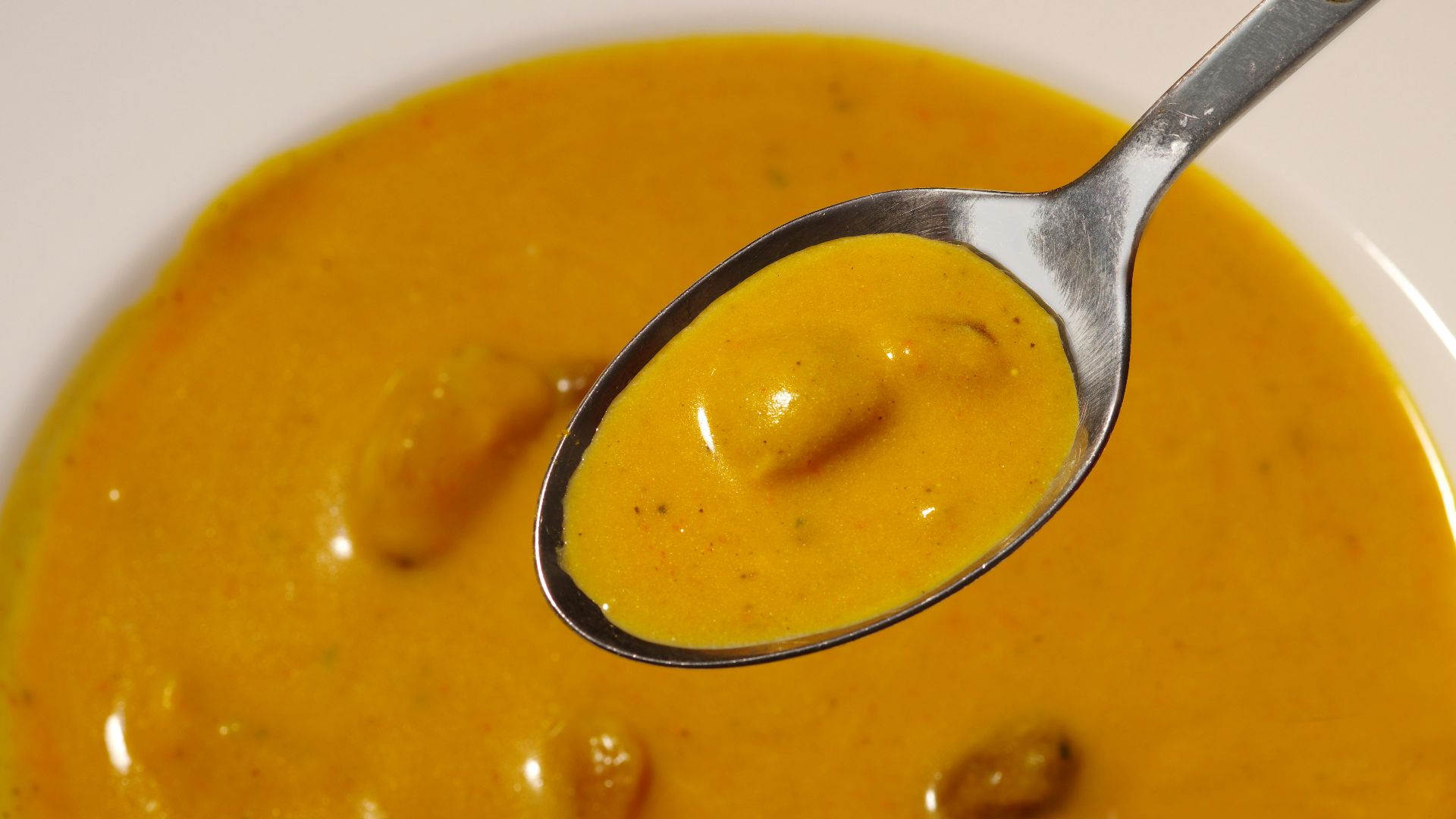 a spoon full of soup on a white plate