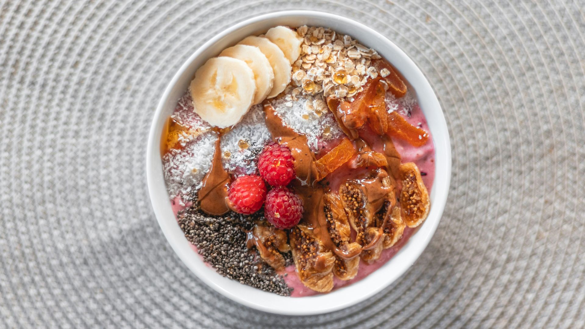 a bowl of food with bananas, raspberries, and powdered sugar