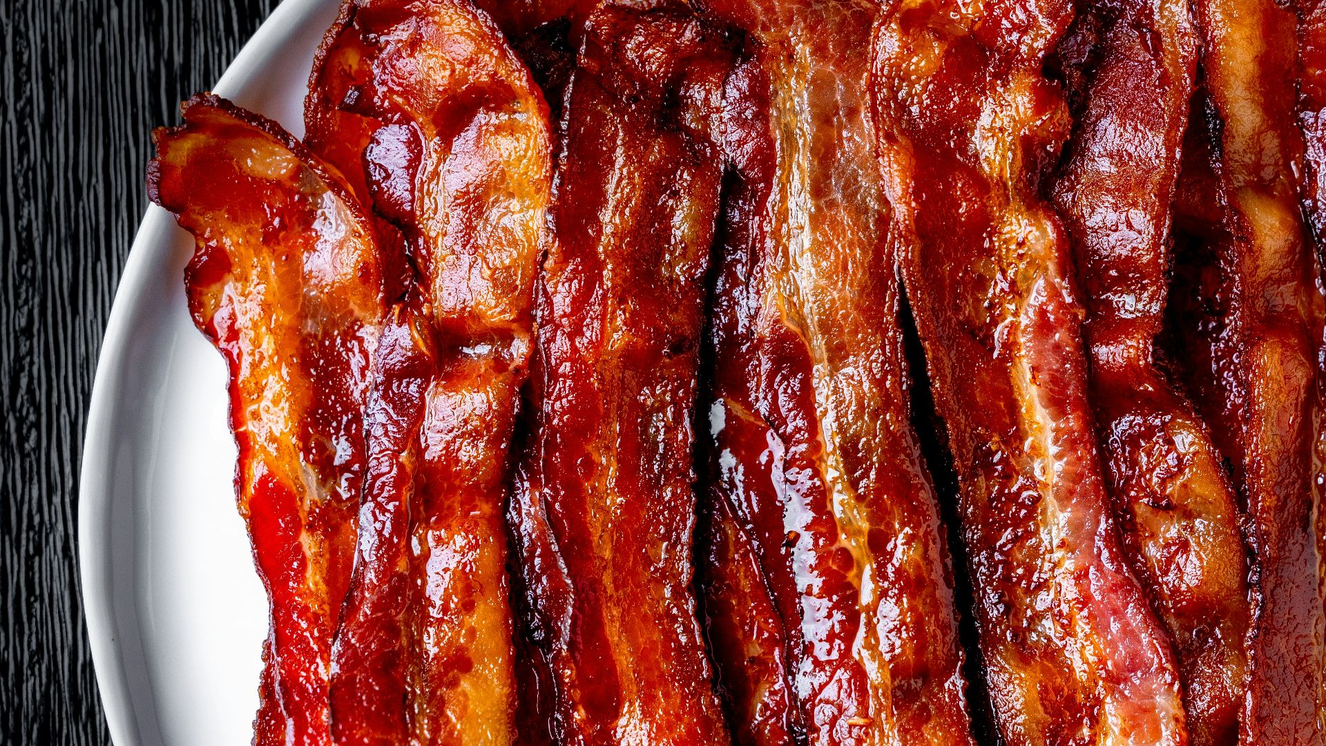 a white plate topped with bacon strips on top of a table