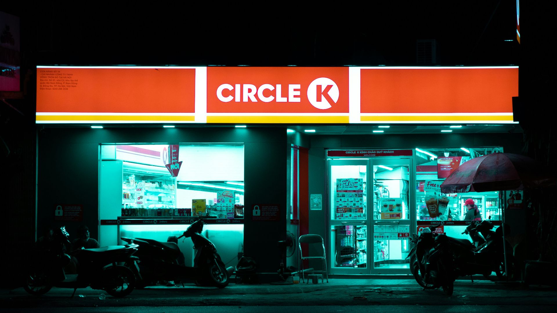 a store front at night with a motorcycle parked in front of it