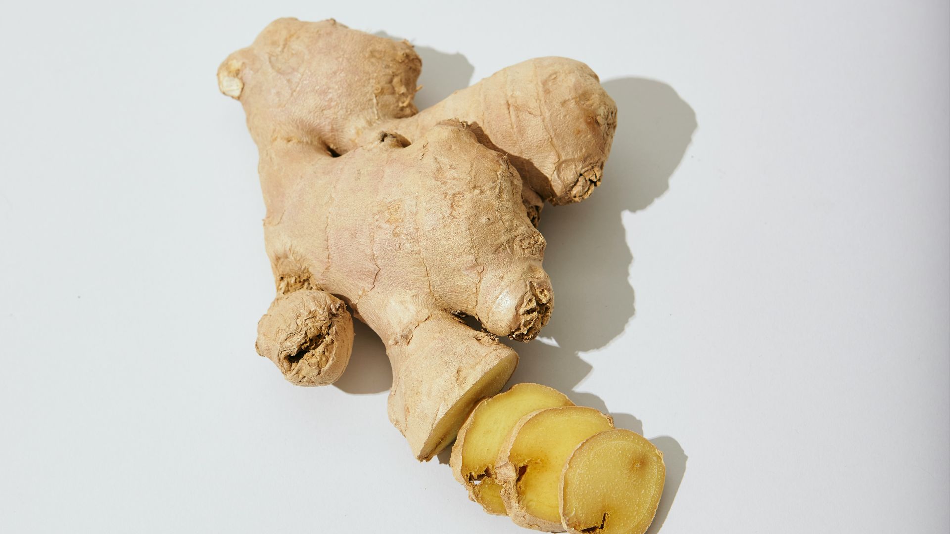 a ginger root and a piece of ginger on a white surface