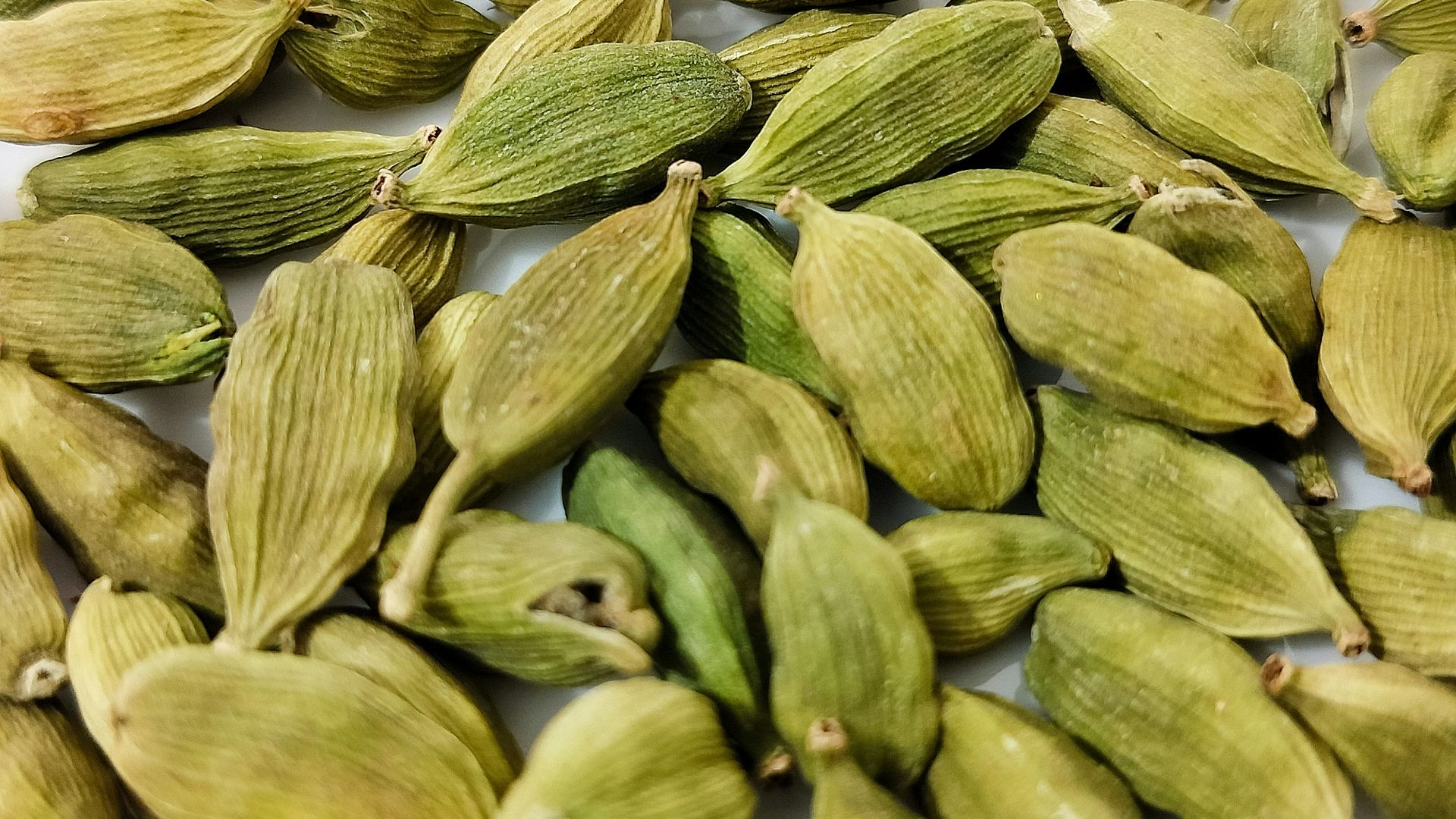 a pile of green seeds on a white surface