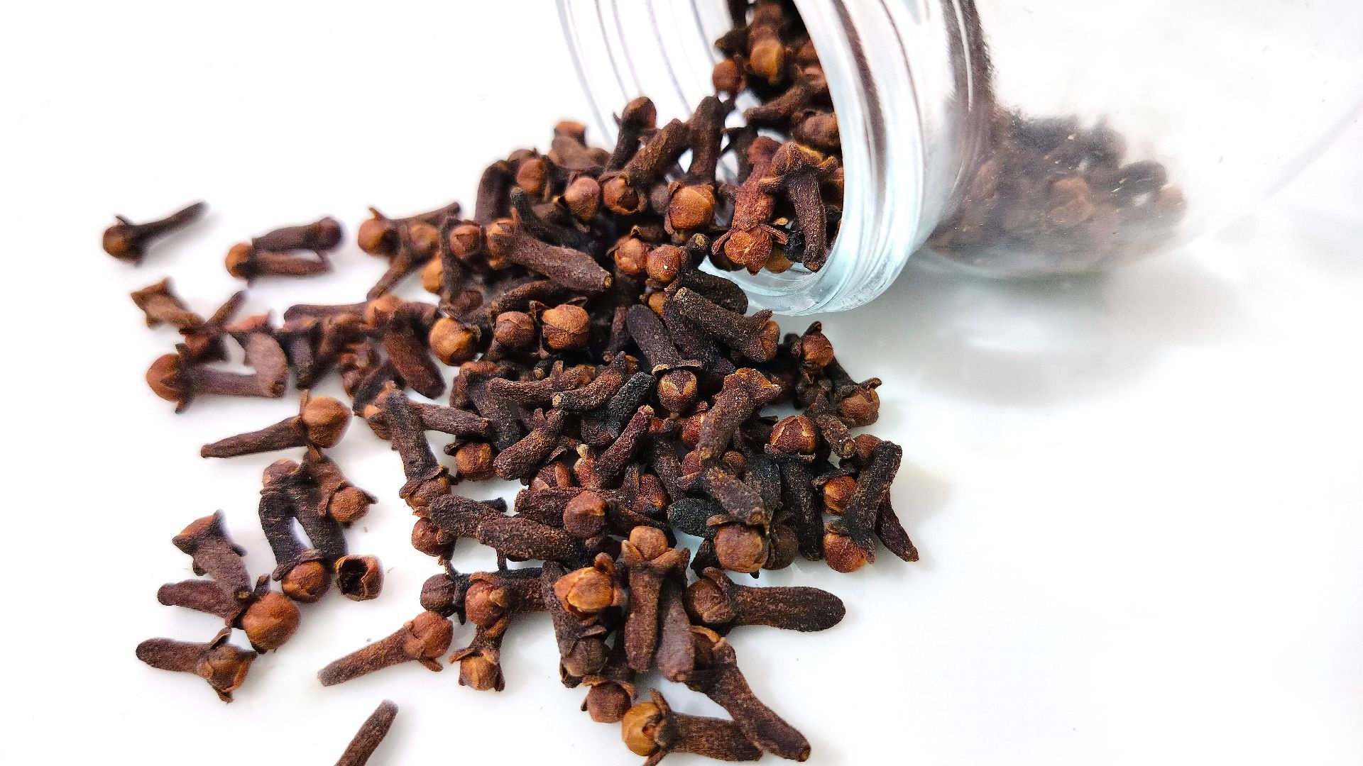 a glass jar filled with cloves on top of a white table