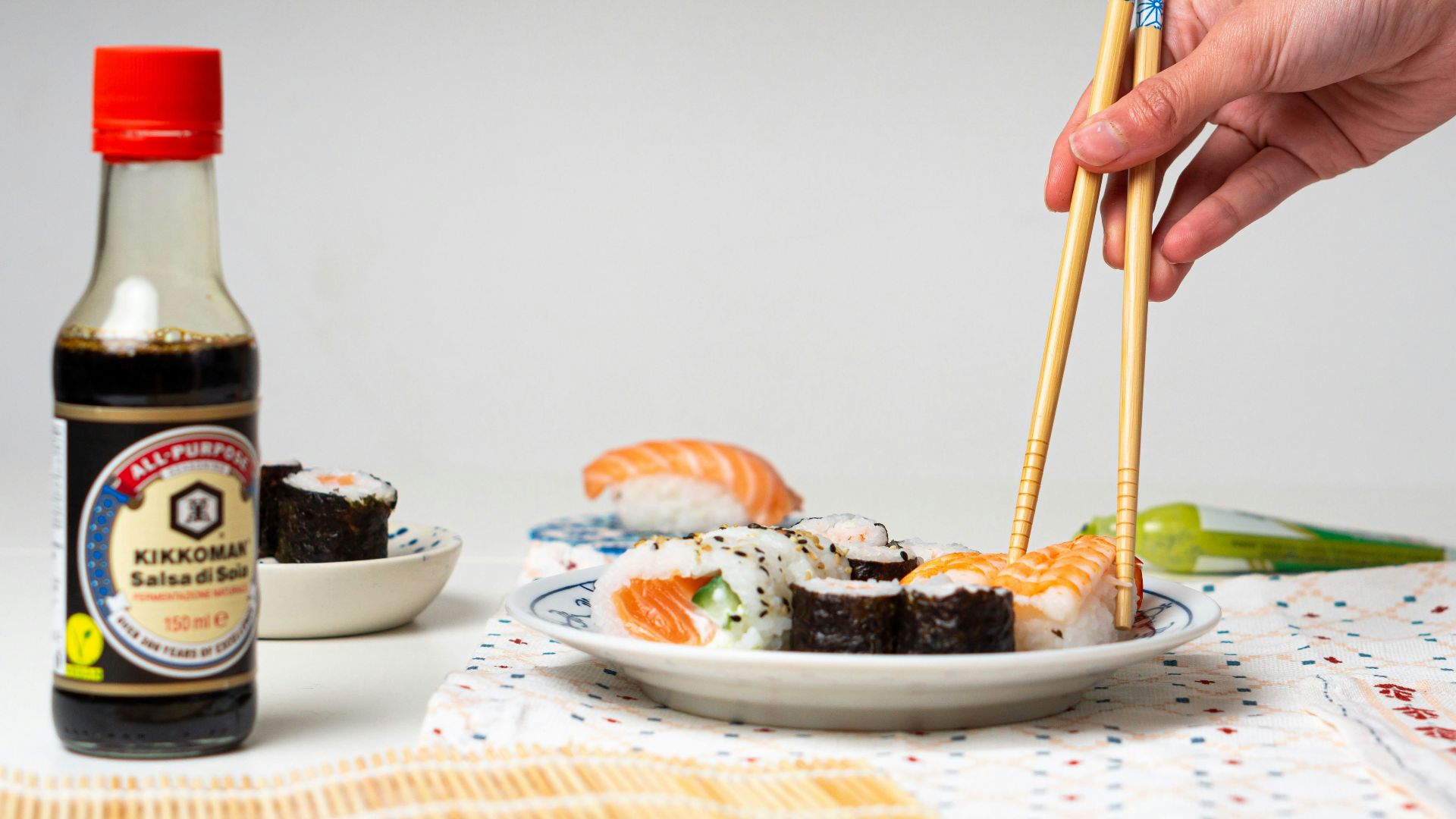 a person holding chopsticks over a plate of sushi