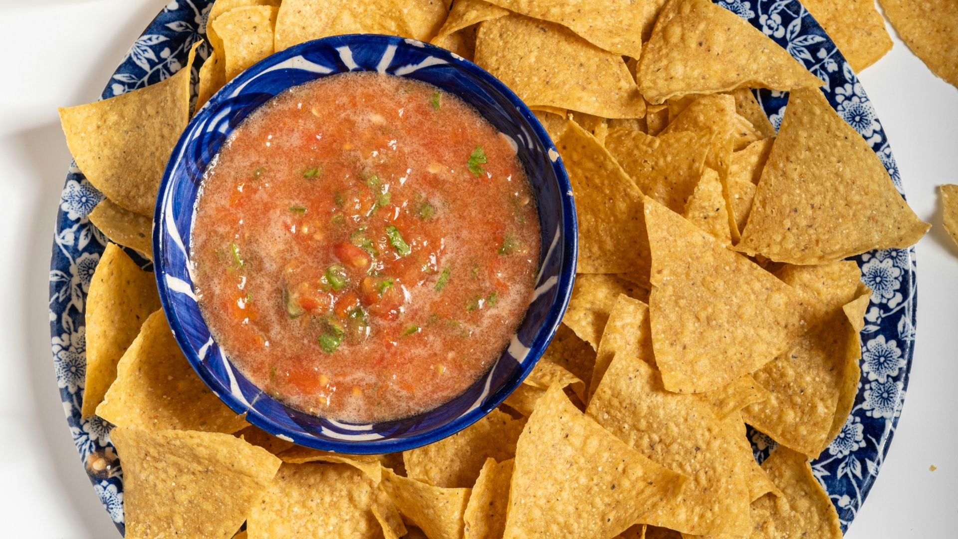 A plate of chips, salsa, and beer on a table