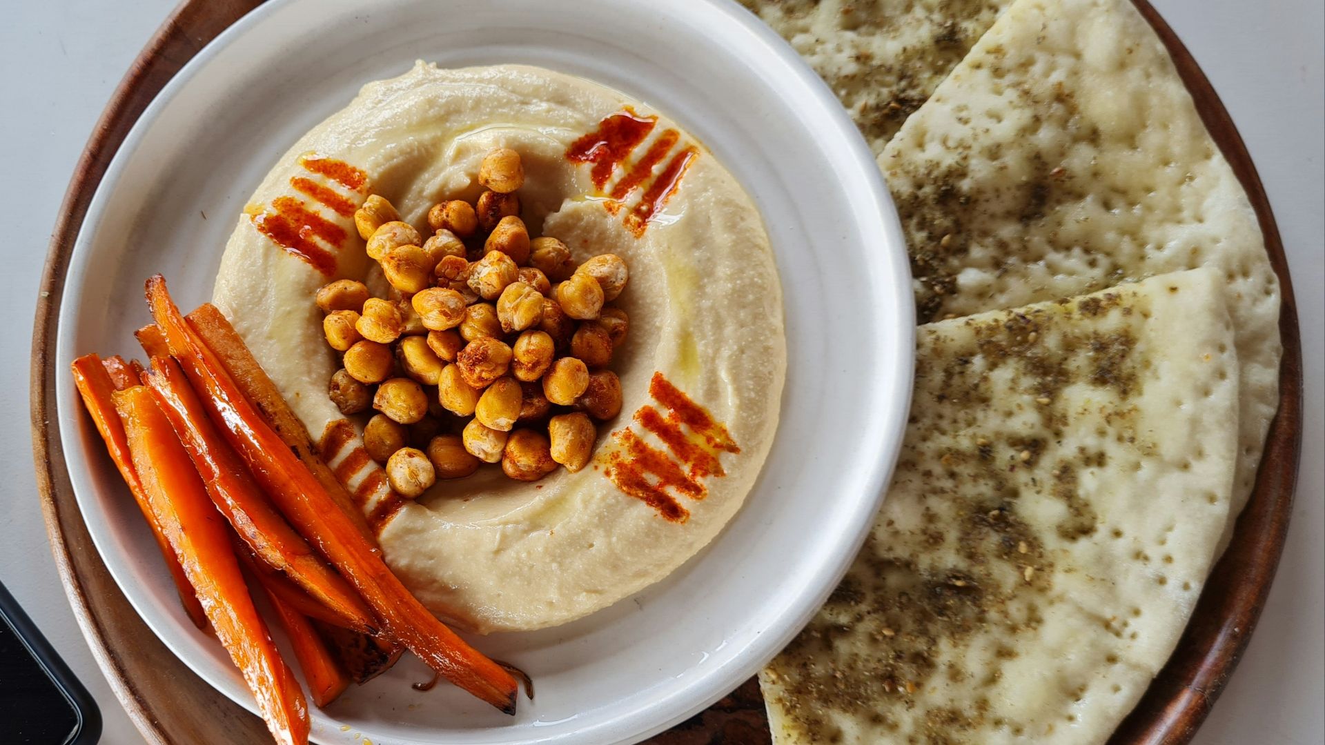 a plate of hummus, carrots, and pita bread