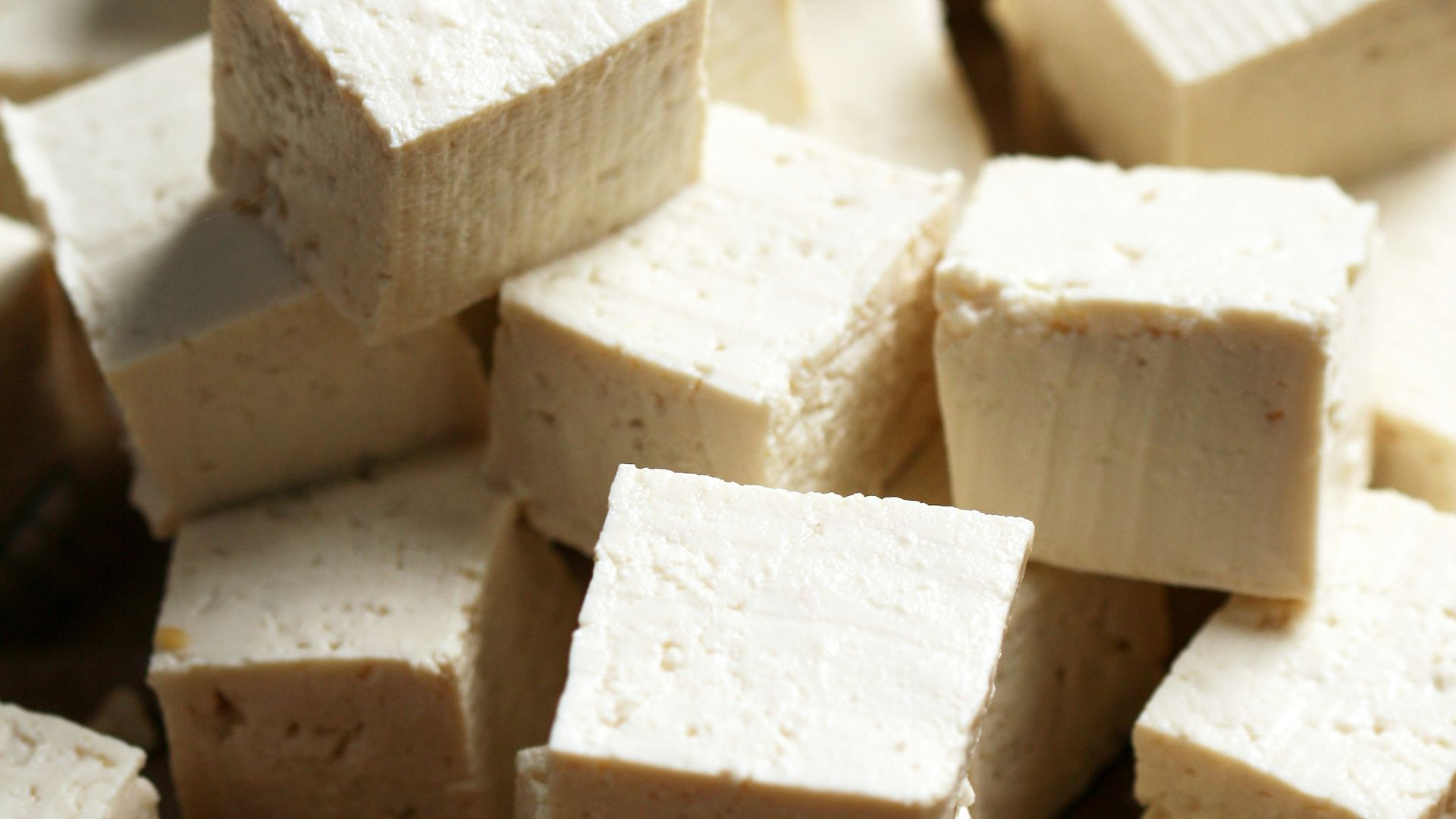 A pile of tofu cubes sitting on top of a cutting board