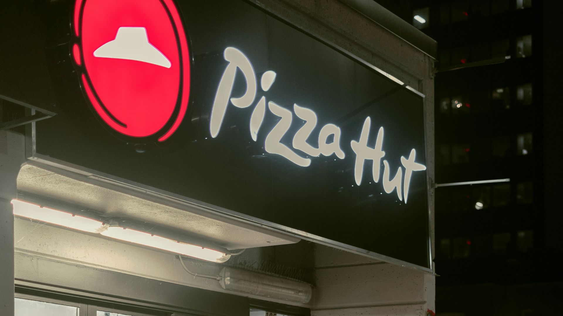 a man riding a bike past a pizza hut