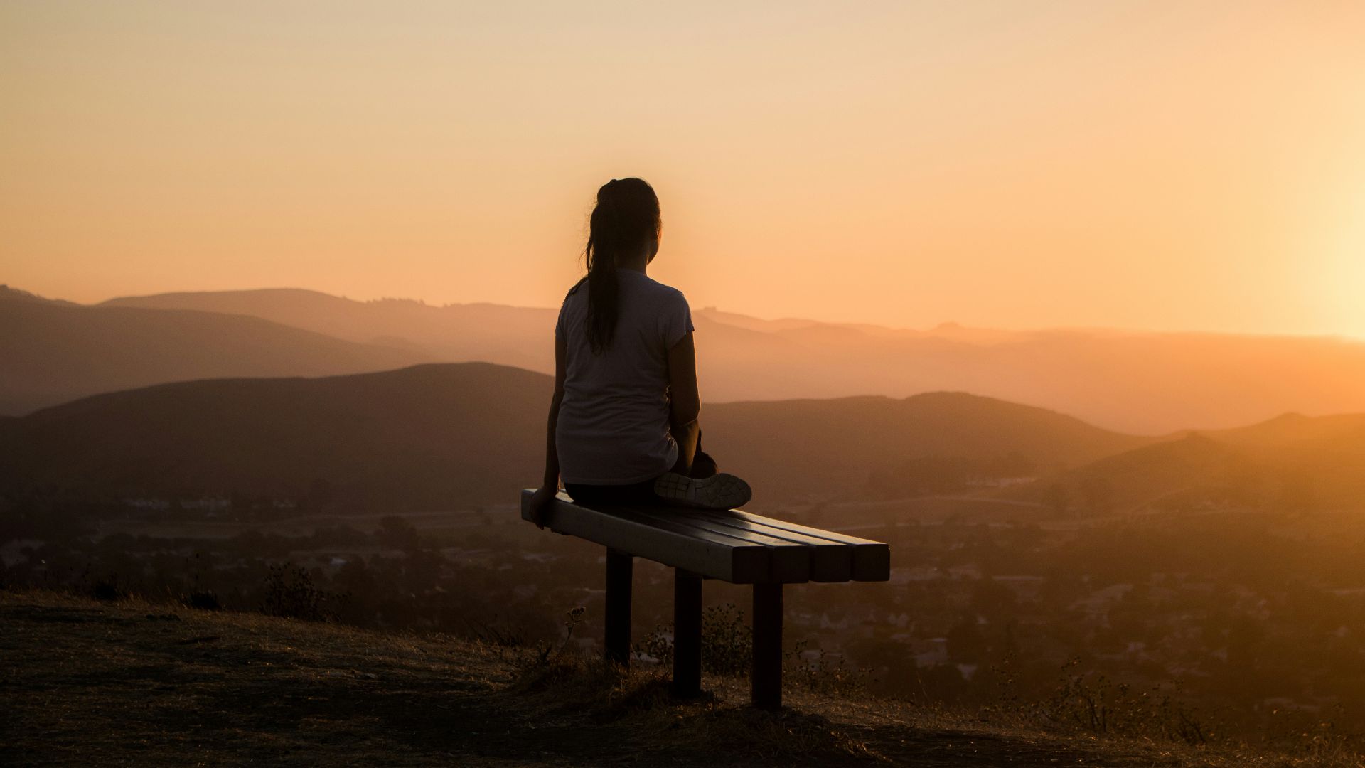 woman sitting on bench over viewing mountain