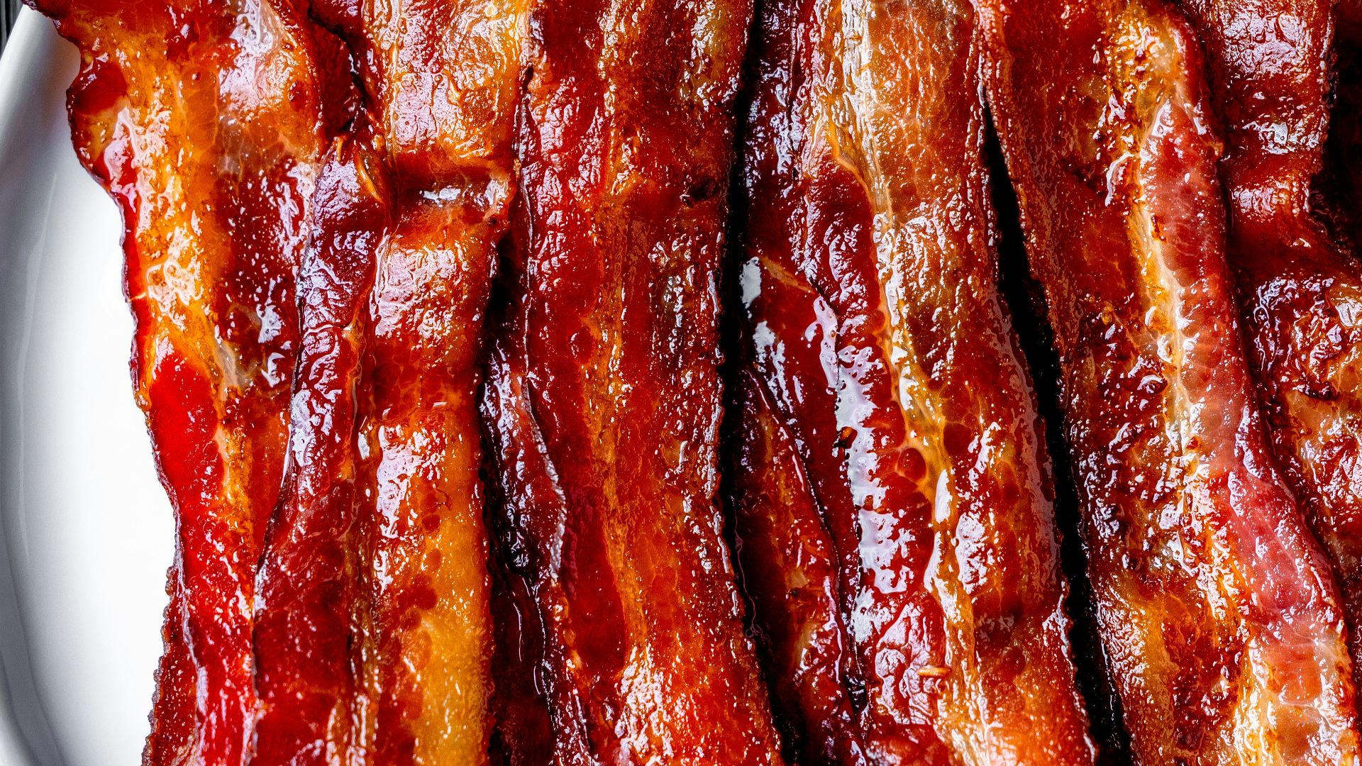 a white plate topped with bacon strips on top of a table